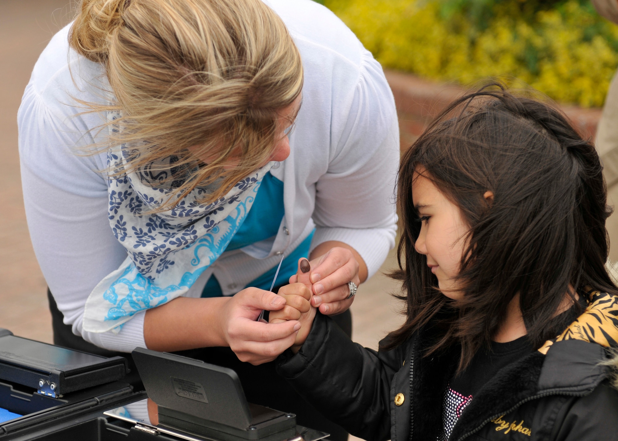 ROYAL AIR FORCE LAKENHEATH, England - Arianna Cirincione, 48th Security Forces Squadron investigator, takes the fingerprints of 5-year-old Victoria Fernandez outside the commissary during National Police Week, May 17, 2011. Police week honors all law enforcement officers for their dedication, sacrifice and service. McGruff the Crime Dog and a weapons display were available in addition to the finger-printing. (U.S. Air Force photo/Senior Airman Tiffany M. Deuel)