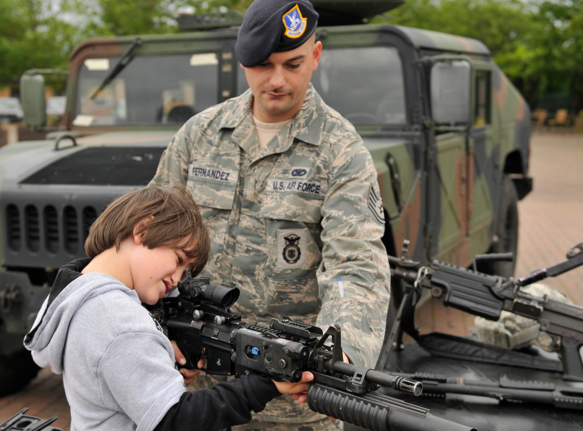 ROYAL AIR FORCE LAKENHEATH, England - Staff Sgt. Shawn Fernandez, 48th Security Forces Squadron instructor, watches Logan Deguchi, RAF Lakenheath Elementary School 3rd grader, handle a M4 with M203 attachment outside the commissary during National Police Week, May 17, 2011. Police week honors all law enforcement officers for their dedication, sacrifice and service. McGruff the Crime Dog and a free finger-printing stand were available in addition to the weapons display. (U.S. Air Force photo/Senior Airman Tiffany M. Deuel)