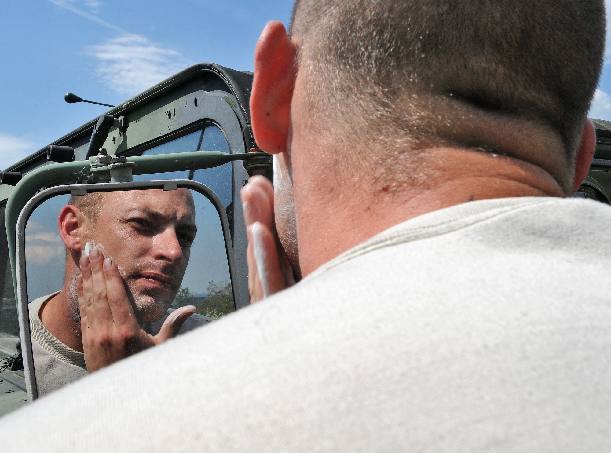 GEROLSTEIN, Germany – Staff Sgt. Dustin Smith, 606th Air Control Squadron power production journeyman, shaves using the side view mirror of a Humvee while participating in exercise Eifel Thunder 2011 here May 10. The 606th ACS participated in a field exercise that tested their ability to deploy and set up a deployed radar and satellite communications site as well as everything else required to accomplish their mission. The squadron returned to Spangdahlem Air Base May 16. (U.S. Air Force photo/Senior Airman Nick Wilson)