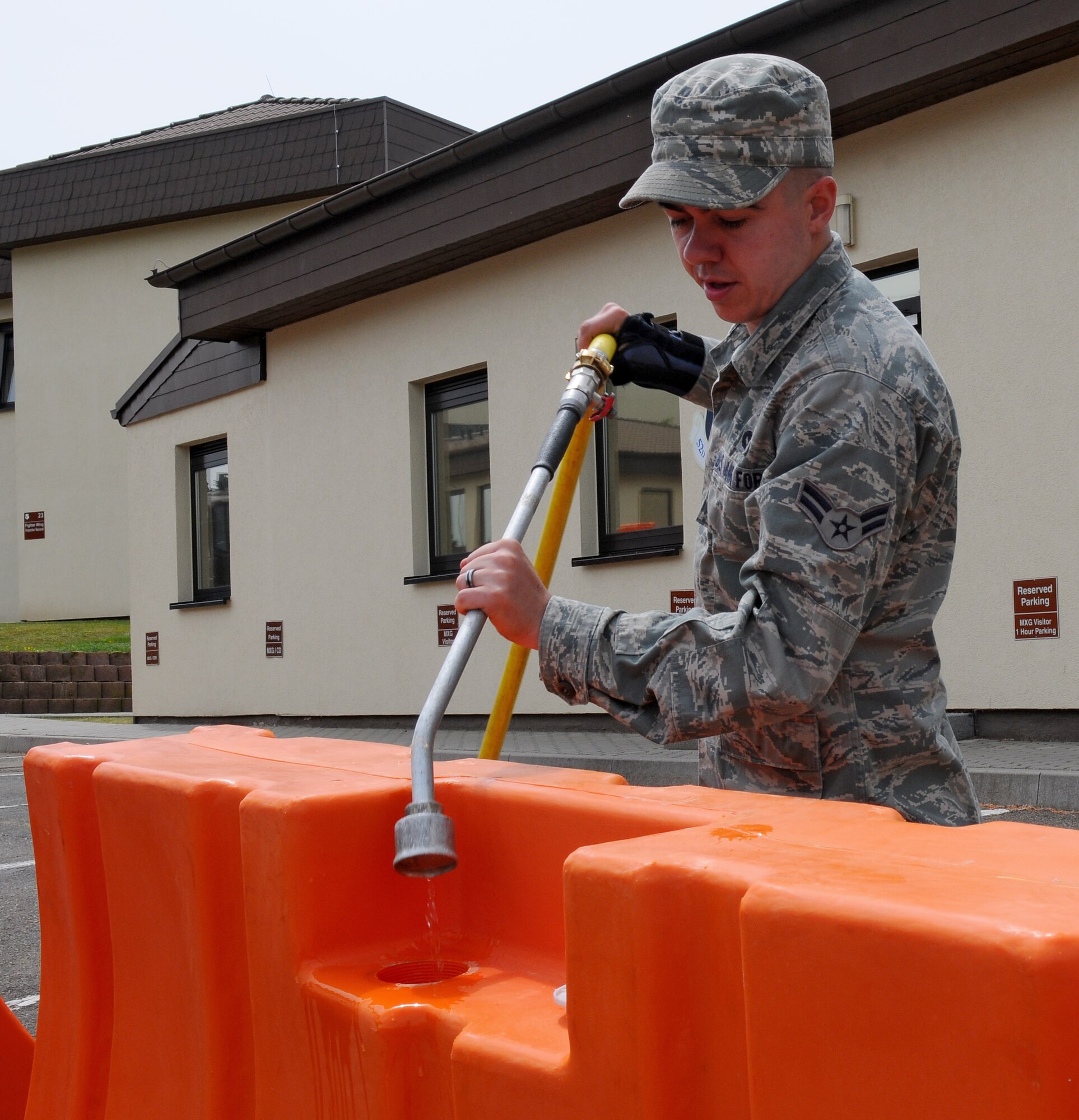 SPANGDAHLEM AIR BASE, Germany – Airman 1st Class Jacob Smith, 52nd Civil Engineer Squadron, uses a water hose to fill a plastic barrier during a barrier plan exercise here May 17. The barrier plan is conducted biannually to ensure Spangdahlem is capable of responding to increased threat levels. (U.S. Air Force photo/Airman 1st Class Dillon Davis)