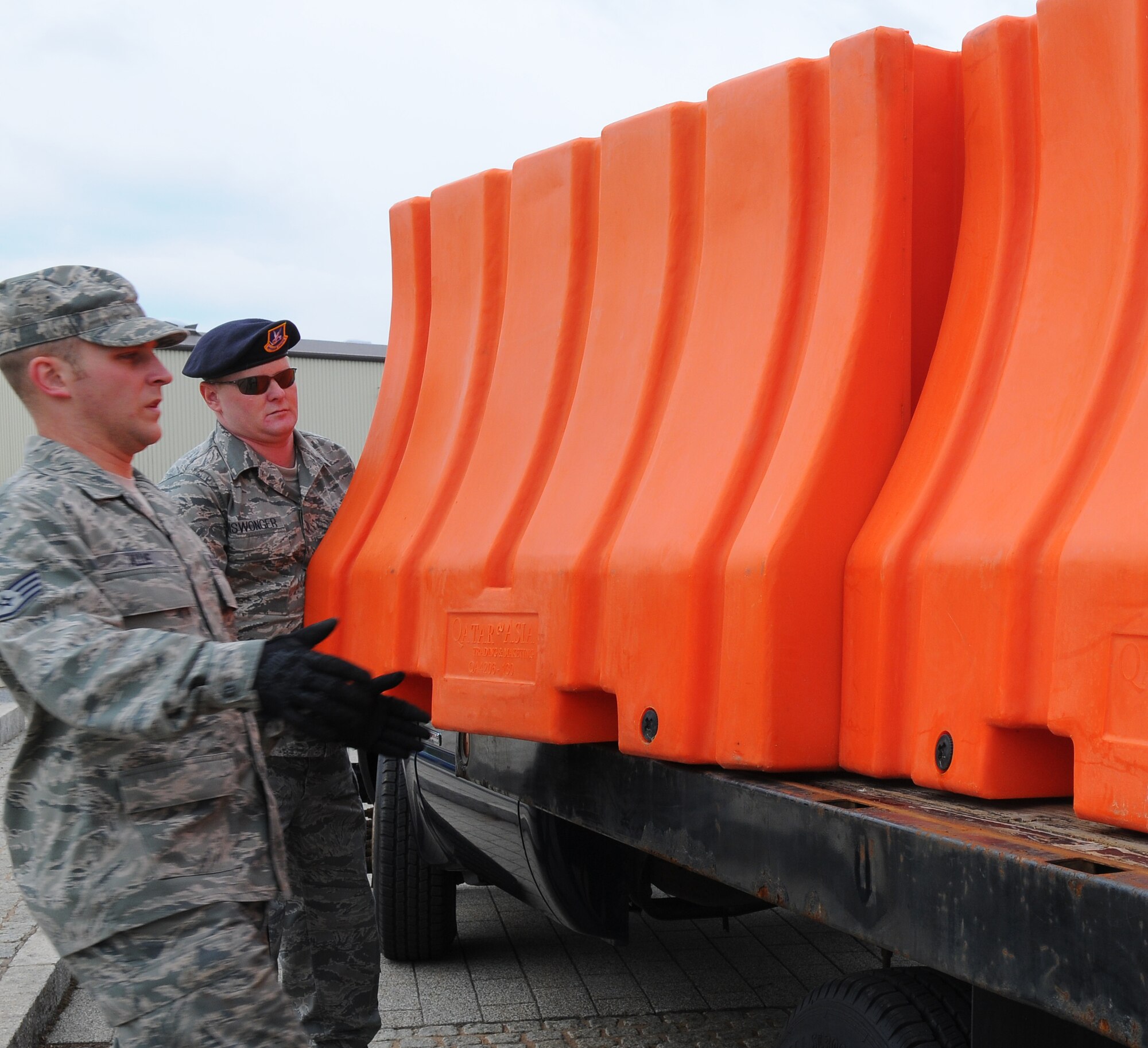 SPANGDAHLEM AIR BASE, Germany – Staff Sgt. Kevin Allie, 52nd Logistics Readiness Squadron, and Tech. Sgt. Paul Niswonger, 52ndFighter Wing Anti-Terrorism Office, unload a barrier from a transport vehicle during a barrier plan exercise here May17. The barrier plan is conducted biannually to ensure Spangdahlem is capable of responding to increased threat levels. (U.S. Air Force photo/Airman 1st Class Dillon Davis)