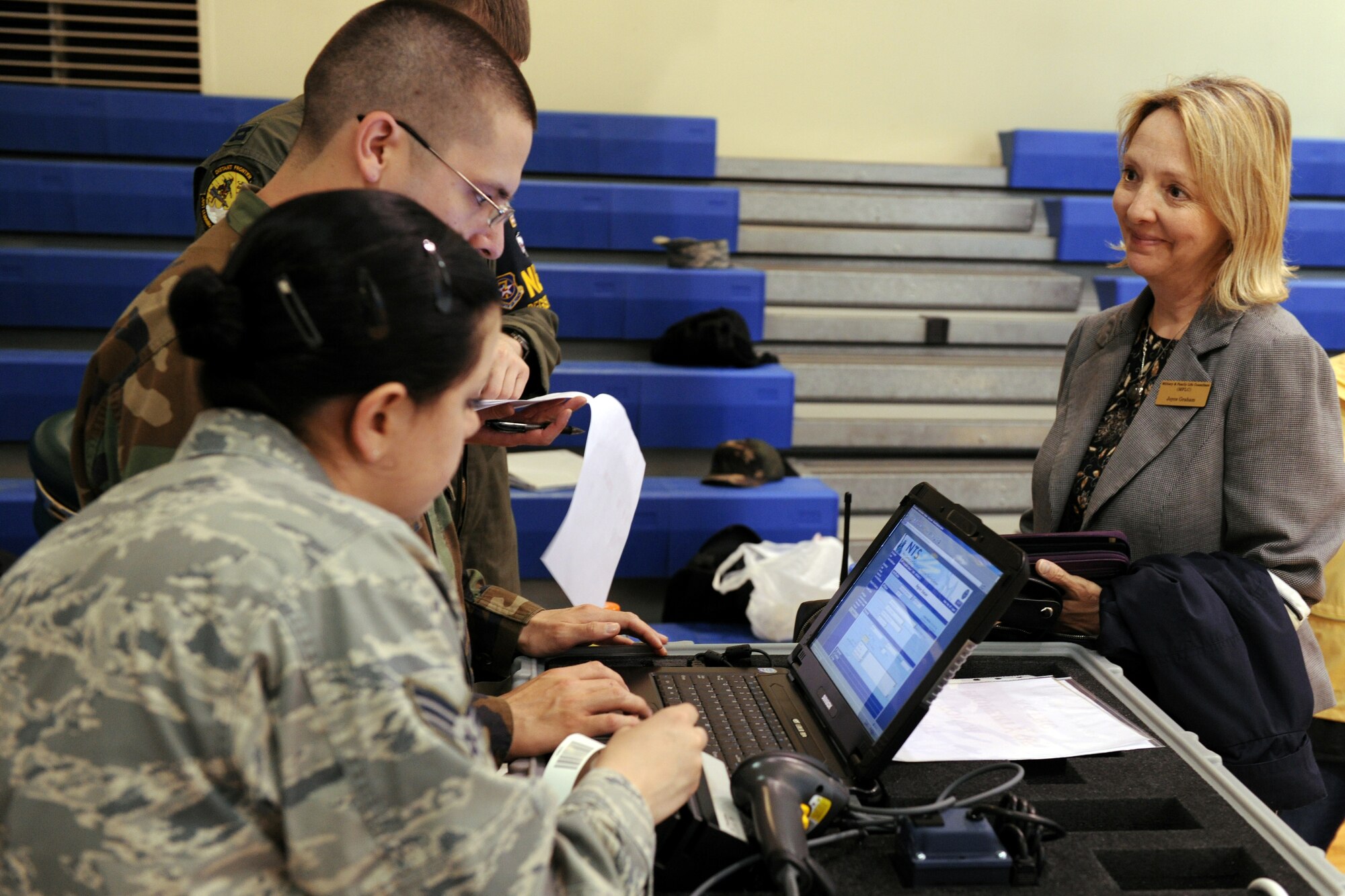 KUNSAN AIR BASE, Republic of Korea -- Senior Airman Jeffrey MacHott, 8th Civil Engineer Squadron operations management, and Senior Airman Jaimee Bettencourt, 8th Medical Operations Squadron biological and environmental technician, checks in Ms. Joyce Graham, a noncombatant participant, at Exercise Courageous Channel here May 19. The exercise is held every spring and organized by the U.S. Forces Korea. It enables U.S. military dependents, non-emergency essential civilians and contractors to walk through the process that would be employed during a noncombatant evacuation. (U.S. Air Force photo/Senior Airman Ciara Wymbs)