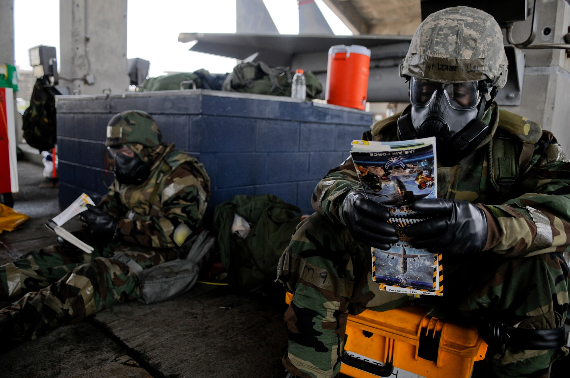 Tech. Sgt. Lendrea Curl, 18th Aircraft Maintenance Squadron aerospace propulsion technician (right), and Airman 1st Class Kevin Buff, 67th Aircraft Maintenance Unit assistant dedicated crew chief, consult their Airman’s Manuals while in mission-oriented protective posture gear as part of Beverly High 11-4, a local operational readiness exercise, on Kadena Air Base, May 19. During a LORE, Airmen are expected to perform and operate in a multitude of different scenarios that they could potential encounter in a real-world situation. (U.S. Air Force photo/ Airman 1st Class Maeson L. Elleman)