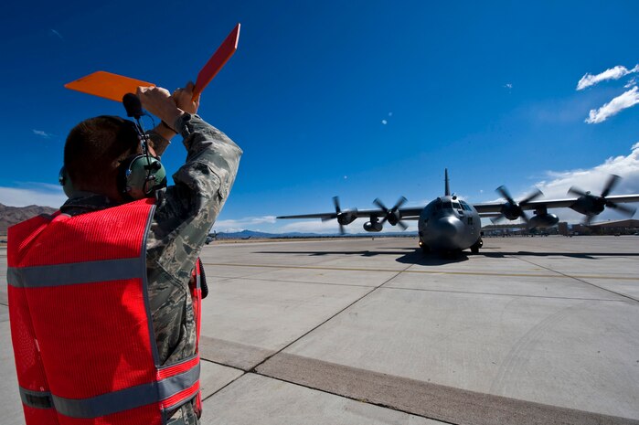 U.S. Air Force Senior Airman Leonard Brown a crew chief with the 615th Contingency Response Wing, Travis Air Force Base, Calif., marshals in a C-130 Hercules at Nellis AFB, Nev., following a Mobility Air Forces Exercise mission May 18. Approximately 40 C-17 Globemaster III and C-130 aircraft assembled in aerial formations over the Nevada Test and Training Range to conduct air and ground operations as part of the bi-annual, U.S. Air Force Weapons School training event. (U.S. Air Force photo/Senior Airman Brett Clashman)
