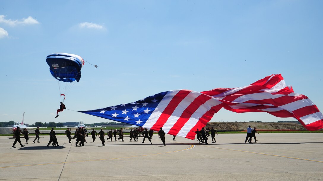 An E-Team Skydiver delivers the U.S. Flag to show center as the Civil Air Patrol catches it from above during the 2011 Joint Service Open House Opening Ceremony here May 21. JSOH affords the public an opportunity to meet the men and women of the Armed Forces and to see military equipment from the Navy, Marines, Army, Air Force and Coast Guard. JSOH is planned and conduct through the efforts of active duty, guard and reserve servicemembers, as well as civilian employees, retirees and family members. (U.S. Air Force photo/ Staff Sgt. Nichelle Anderson)