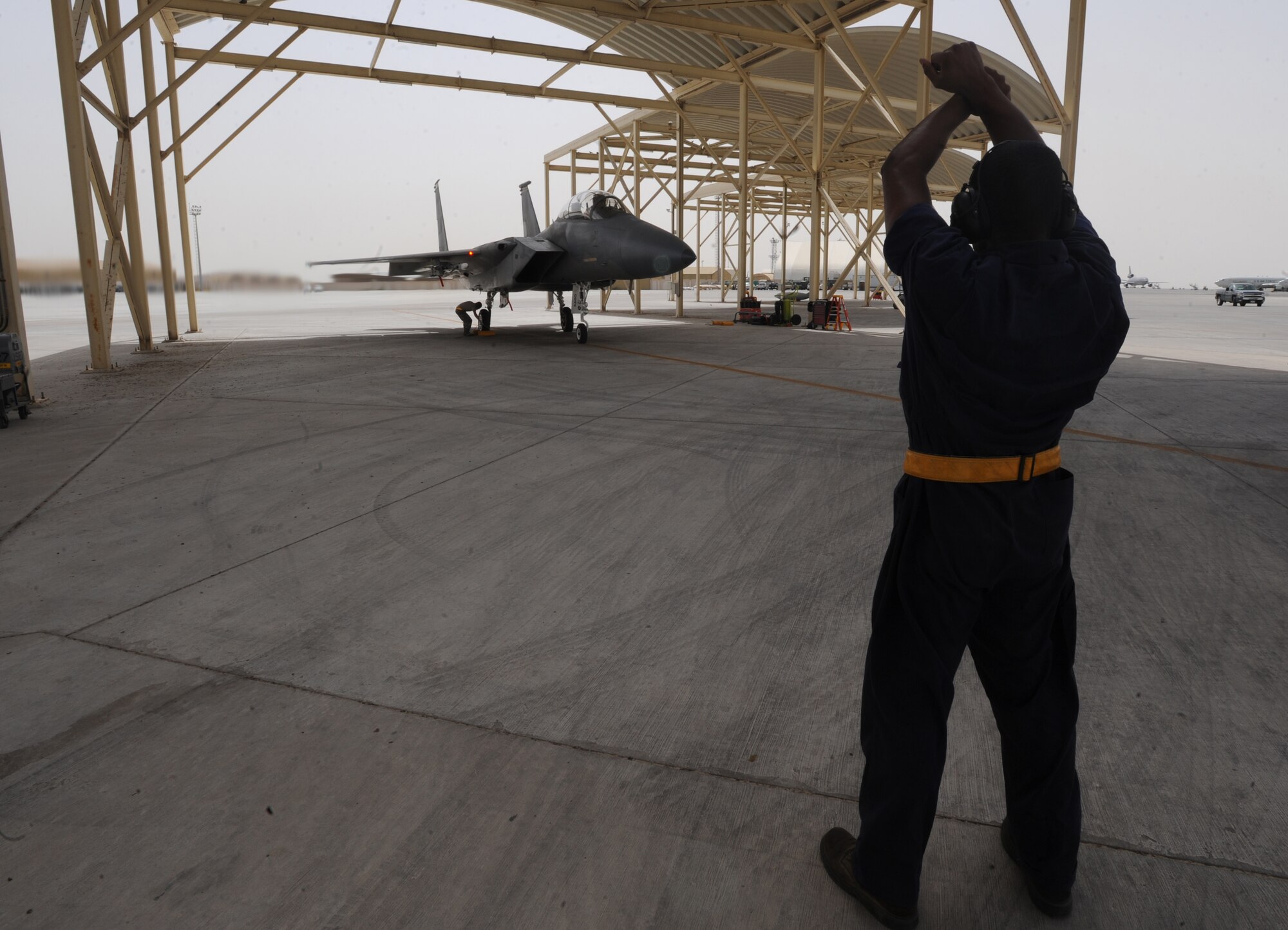 Airman Brian Carter, 380th Expeditionary Aircraft Maintenance Squadron, gives the pilot directions as he pulls out of the F-15C Eagle's shelter May 3, 2011. Given that the pilot has a few blind spots, a spotter ensures a safe path for the aircraft as it taxis onto the ramp. Airman Carter is deployed from Lakenheath AB, U.K. (U.S. Air Force photo by Senior Airman Maynelinne De La Cruz) 