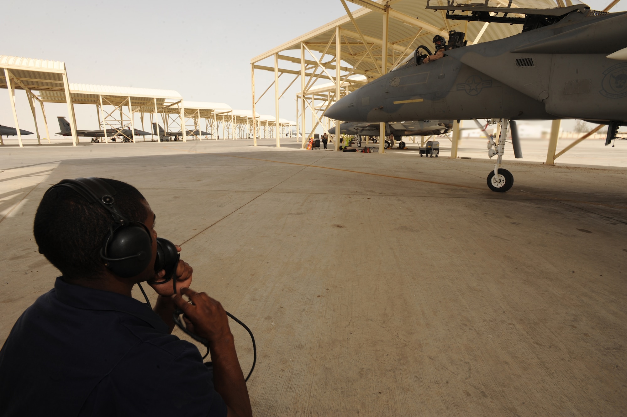 Airman Brian Carter, 380th Expeditionary Aircraft Maintenance Squadron, communicates with the pilot as he tests the controls of the wings on the F-15C Eagle aircraft May 3, 2011. The F-15 can detect and track aircraft and small high-speed targets at distances beyond visual range down to close range, and at altitudes down to treetop level. Airman Carter is deployed from Lakenheath AB, U.K. (U.S. Air Force photo by Senior Airman Maynelinne De La Cruz)  