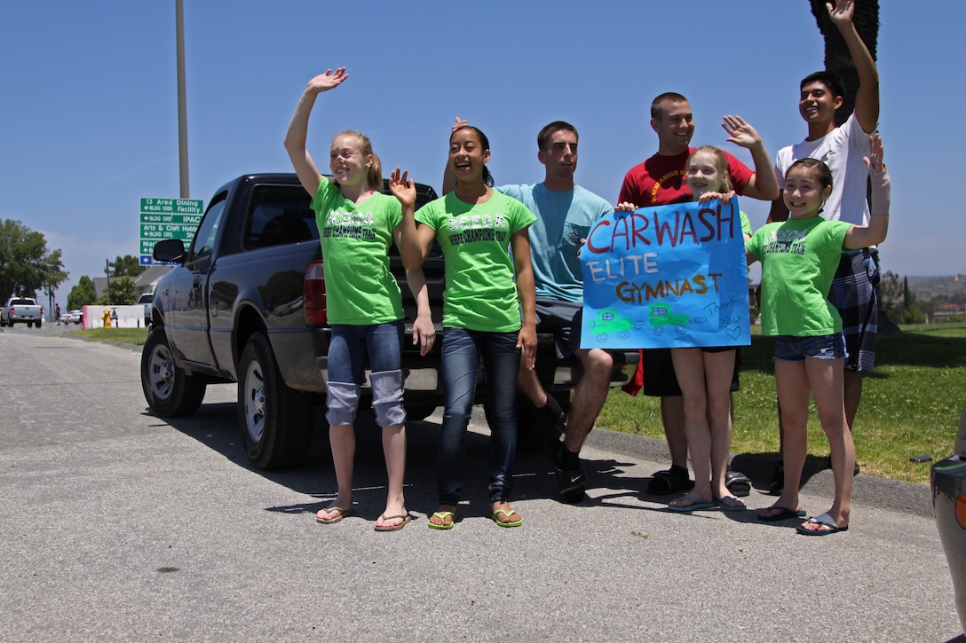 Marines with the command element of the 15th Marine Expeditionary Unit (MEU) and gymnasts with Southern California Elite Gymnastics Academy (SCEGA), advertise their car wash fundraiser on Camp Pendleton’s Main side they are holding to raise money for their program, May 21. Marines with the 15th MEU’s command element spent this Saturday volunteering on base at a car wash fundraiser for a gymnastics club. The event was an excellent opportunity for the unit’s service members to volunteer their time helping others.