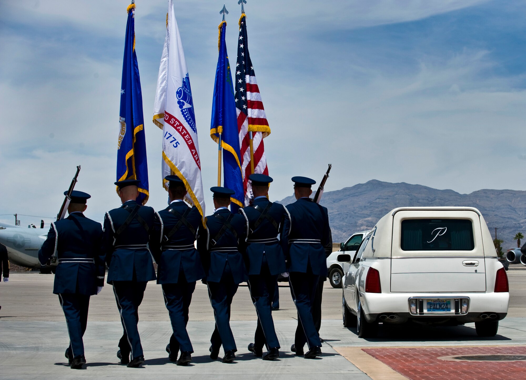 NELLIS AIR FORCE BASE, Nev.--A U.S. Air Force color guard team marches past a ahearse containing the remains of U.S. Army Sgt. Ken Hermogino, at Nellis AFB, May 21, 2011. Sergeant Hermogino died May 9 in Herat province, Afghanistan, of injuries sustained in a non-combat related vehicle accident. Sergeant Hermogino graduated from Basic High School in Las Vegas in 1998 and, prior to transitioning to the U.S. Army in 2009, he served eight years in the U.S. Air Force as a medical administrator. He will be laid to rest with full military honors at the Southern Nevada Veterans Memorial Cemetery in Boulder City. (U.S. Air Force photo/Senior Airman Brett Clashman)