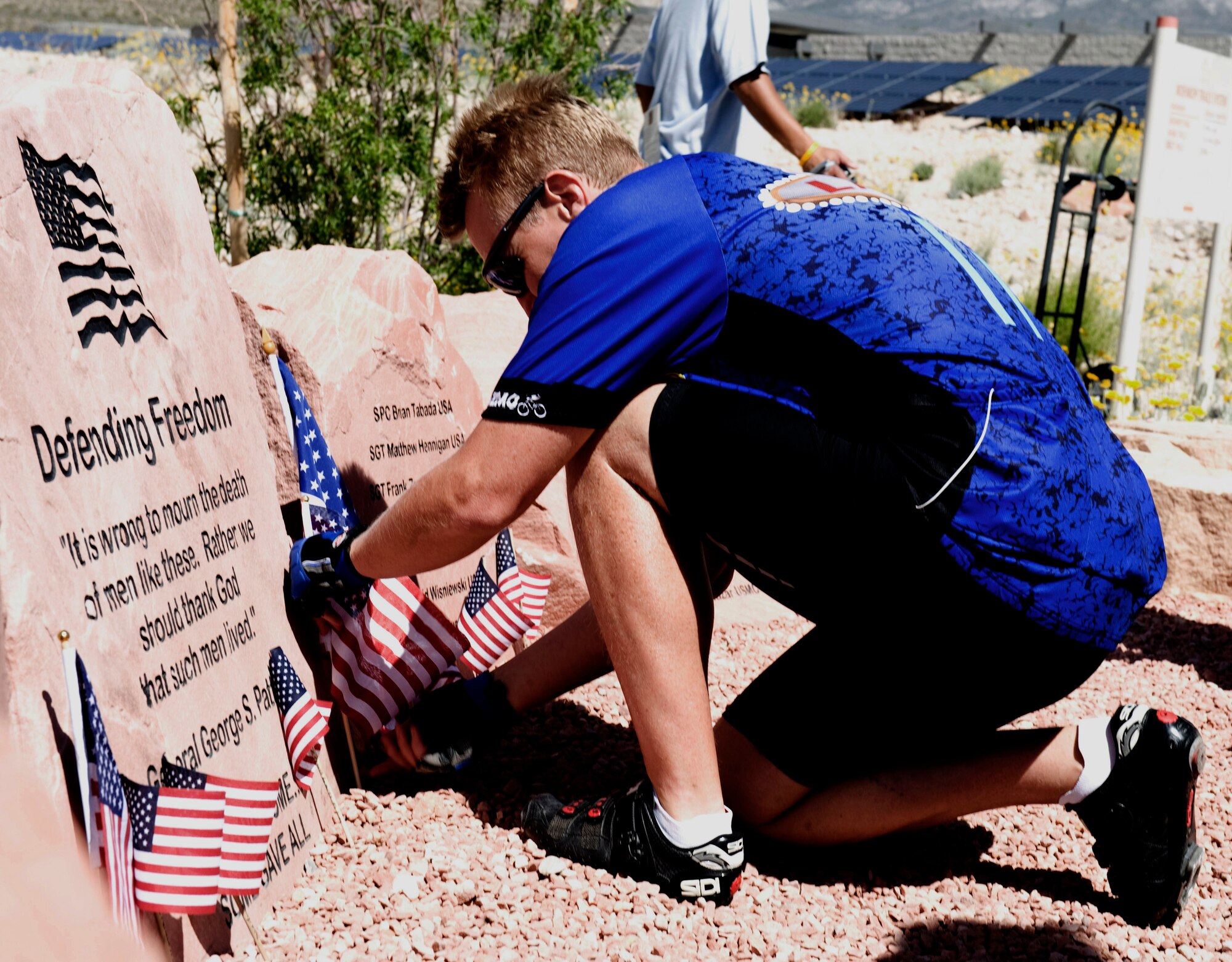 LAS VEGAS -- A bicyclist places a flag at the foot of the Defending Freedom Memorial at Red Rock National Conservation Area, Las Vegas, May 14. The Defending Freedom Memorial honors fallen servicemembers with ties to Nevada and provides a forum for the community to express its appreciation for this sacrifice. The Defending Freedom Memorial was initially dedicated in 2005 and is comprised of seven sandstones with the engraved names of Nevada's fallen servicemen and women.  (U.S. Air Force photo by Airman 1st Class Jamie L. Nicley)