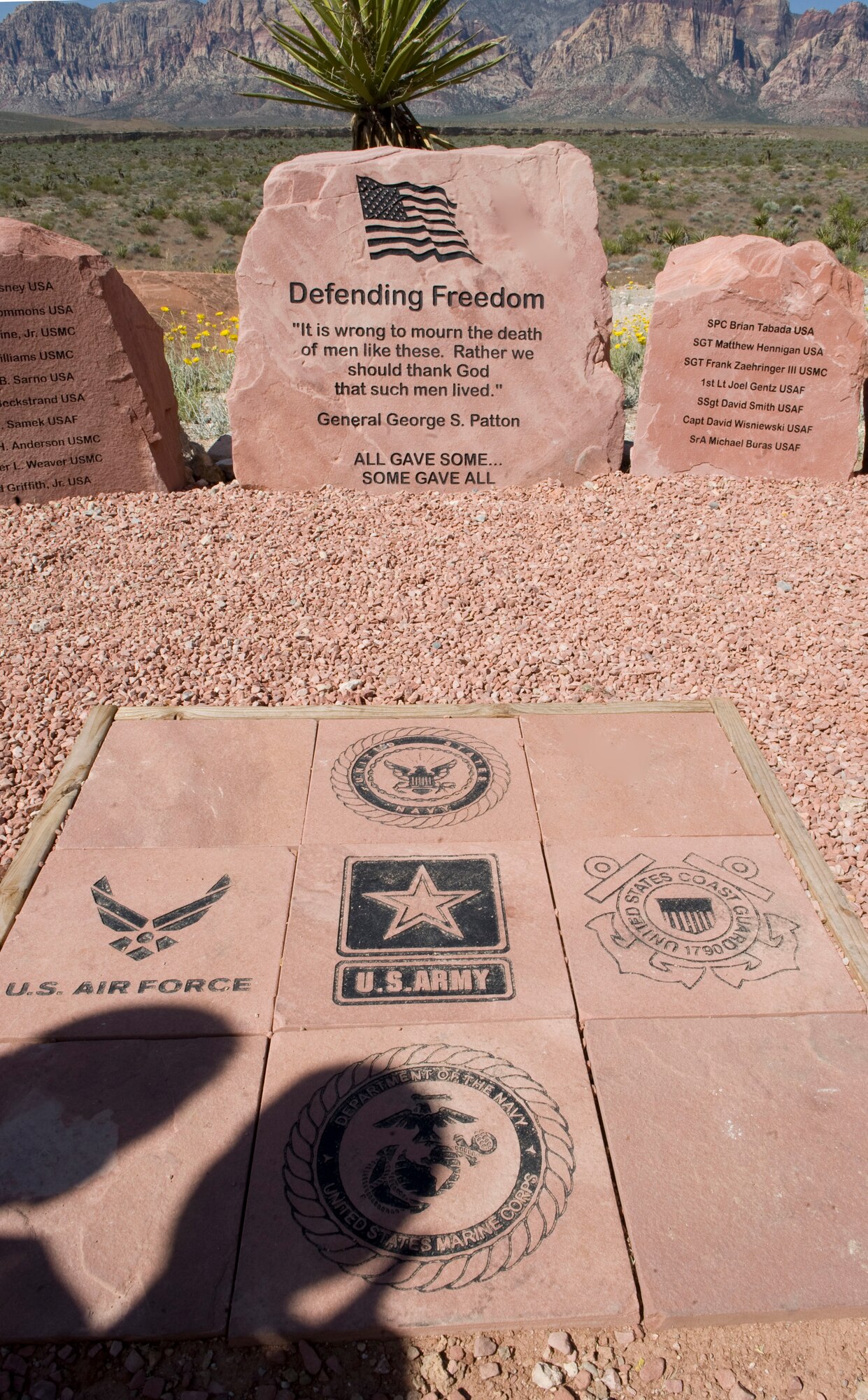 LAS VEGAS --The shadows of Nevada Congressman Joe Heck and his son, Joseph, are visible as they pay their respects at the Defending Freedom Memorial at Red Rock National Conservation Area May 14, 2011. Congressman Heck was a guest speaker at  the 6th annual Defending Freedom Memorial dedication ceremony. Hosted annually, the event honors fallen servicemembers with ties to Nevada and provides a forum for the community to express its appreciation for this sacrifice. The Defending Freedom Memorial was initially dedicated in 2005 and is comprised of seven sandstones with the engraved names of Nevada's fallen servicemen and women. This year, the names Nellis Airmen Senior Airman Michael Buras, Staff Sgt. David Smith, 1st Lt. Joel Gentz and Capt. David Wisniewski were added to the memorial. All four Airmen were lost in 2010 while supporting operations in Afghanistan.  (U.S. Air Force photo by Airman 1st Class Jamie L. Nicley)