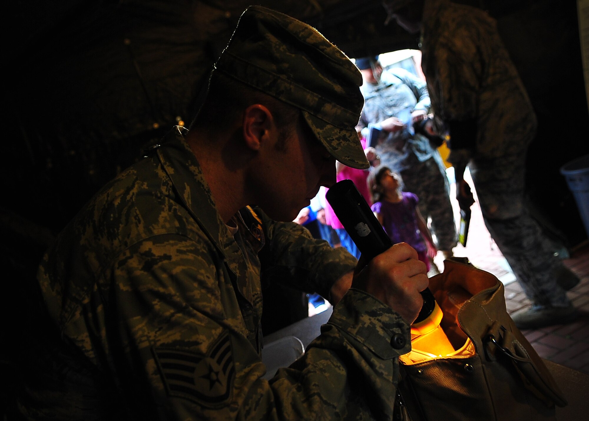 A 51st Fighter Wing Airman searches a bag during process line for U.S. military dependents, non-emergency essential civilians and contractors May 20. Individuals are participating in the Courageous Channel exersice which is held every spring to train servicemembers on registration and evacuation processes. (U.S. Air Force photo/Senior Airman Evelyn Chavez)