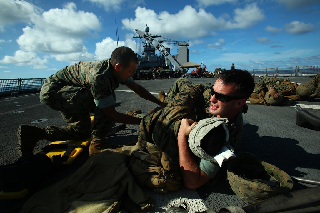 Petty Officer 3rd Class Charles Turner (left), hospital corpsman, landing force command element, checks a simulated victim for back injuries while Petty Officer 3rd Class Alexander Hernandez, hospital corpsman, landing force command element, rotates and immobilizes him. The corpsmen were conducting a casualty evacuation drill prior to a machine gun live-fire drill May 23 aboard the amphibious transport dock ship USS Tortuga (LSD 46). The Marines and Sailors are participating in Cooperation Afloat Readiness and Training (CARAT) 2011. CARAT is a series of bilateral exercises held between U.S. and Southeast Asian defense forces with the goals of enhancing regional cooperation, promoting mutual trust and understanding, and increasing operational readiness. (U.S. Marine Corps Photo by Cpl. Aaron Hostutler)