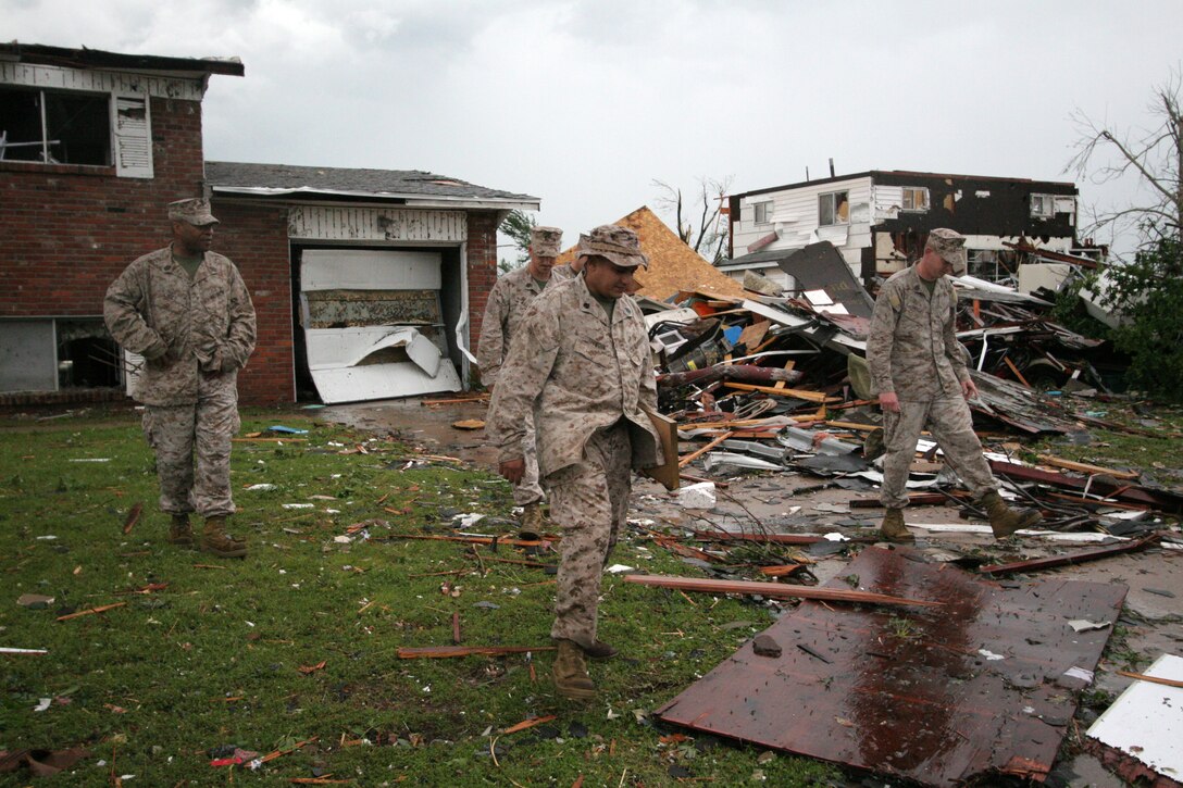 Staff Sgt. Neville Shiwdin (center) and his fellow Marines look over his family's home in Joplin, Mo. May 23 after it's destruction by a tornado the night before. During the tornado, Shiwdin struggled to keep the door closed on their home's closet where he, his wife and kids took shelter. Shiwdin is a recruiter at Recruiting Sub Station Joplin, Recruiting Station Kansas City.