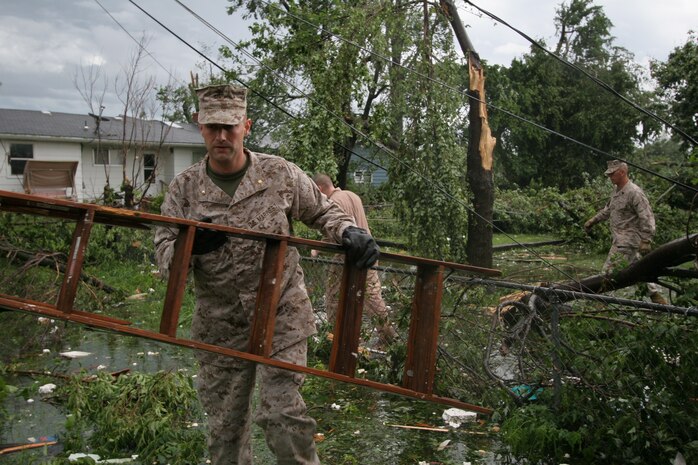 Maj. Thomas McGee finds a ladder among debris so that he and others can begin patching one of his Marine's roof May 23 after it was damaged by a tornado that ripped through Joplin the night before. McGee is the commanding officer of Recruiting Station Kansas City.