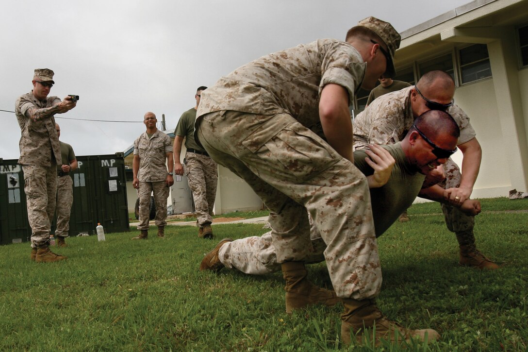 Marines and sailors with Special Operations Training Group and Military Police Support Company, III Marine Expeditionary Force Headquarters Group, III MEF, demonstrate how to operate an X-26 Taser during sustainment training on Camp Hansen May 23.