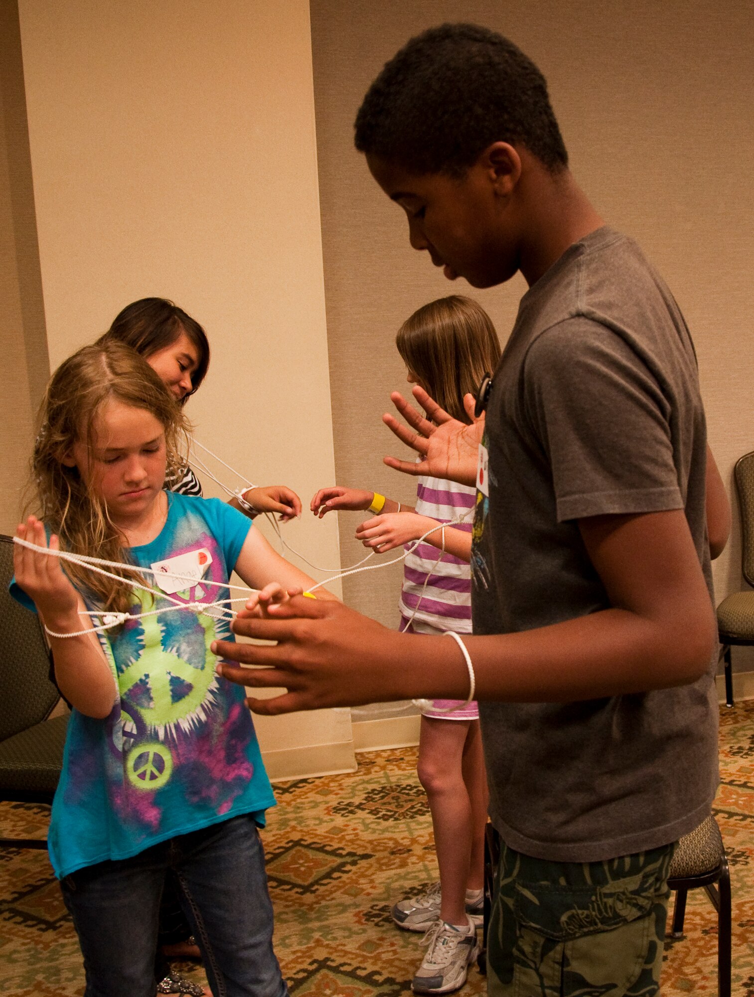 Pre-teens and teenagers maneuver their way out of Houdini’s Handcuffs during a game designed to teach them to work together to solve problems. The children participated in many games that taught them leadership, communication and problem-solving skills during the western regional Yellow Ribbon Event, May 14-15 at the Tempe Mission Palms Resort in Tempe, Ariz. (U.S. Air Force Photo/Staff Sgt. Erin Smith)