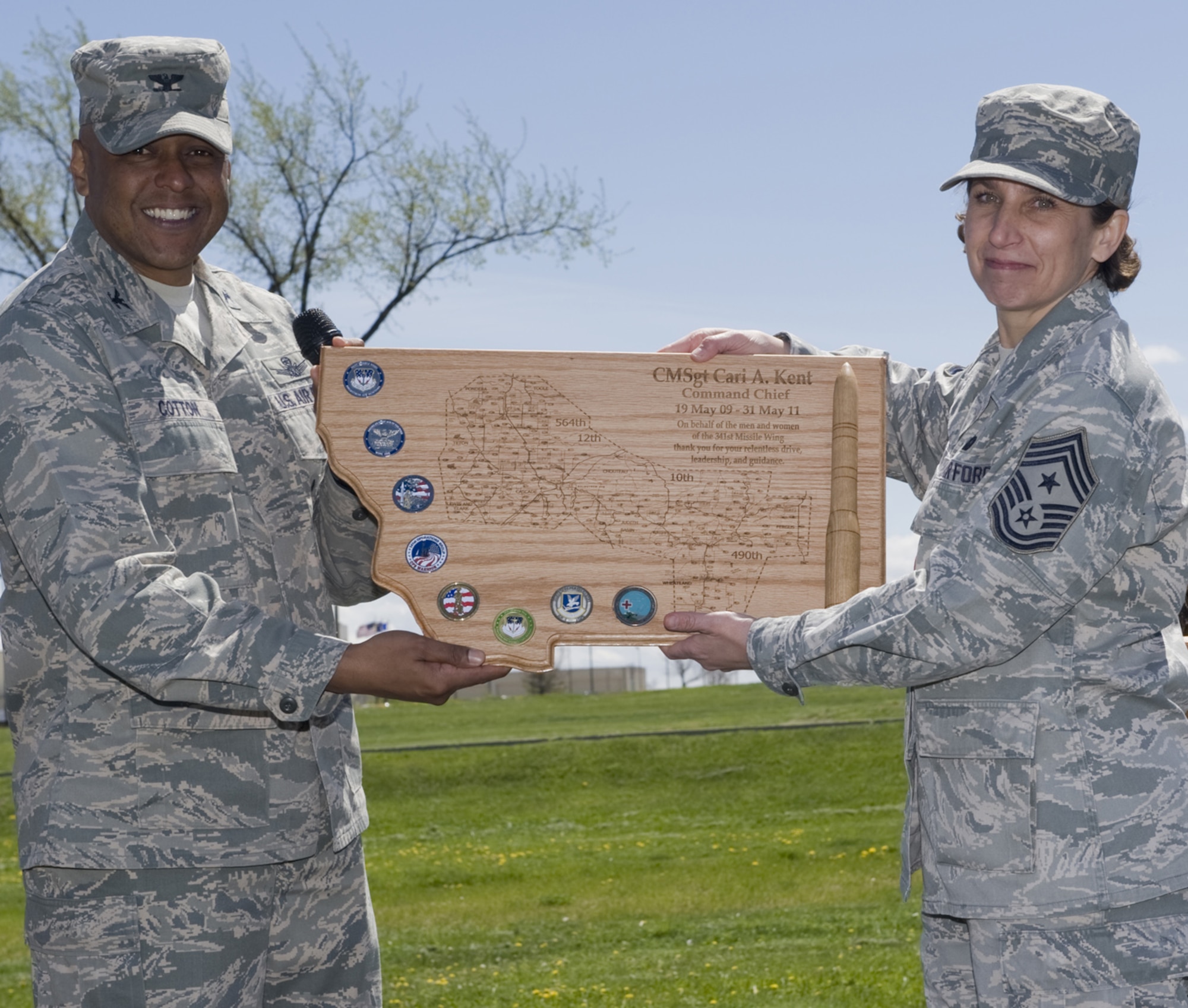 Brig. Gen. (Sel) Anthony Cotton, 341st Missile Wing commander, and Chief Master Sgt. Cari Kent, 341st MW command chief, pose with the going away gift the commander presented her May 17. The wing honored Chief Kent for her service as the command chief during a luncheon at Sun Plaza Park. (U.S. Air Force photo/Beau Wade)