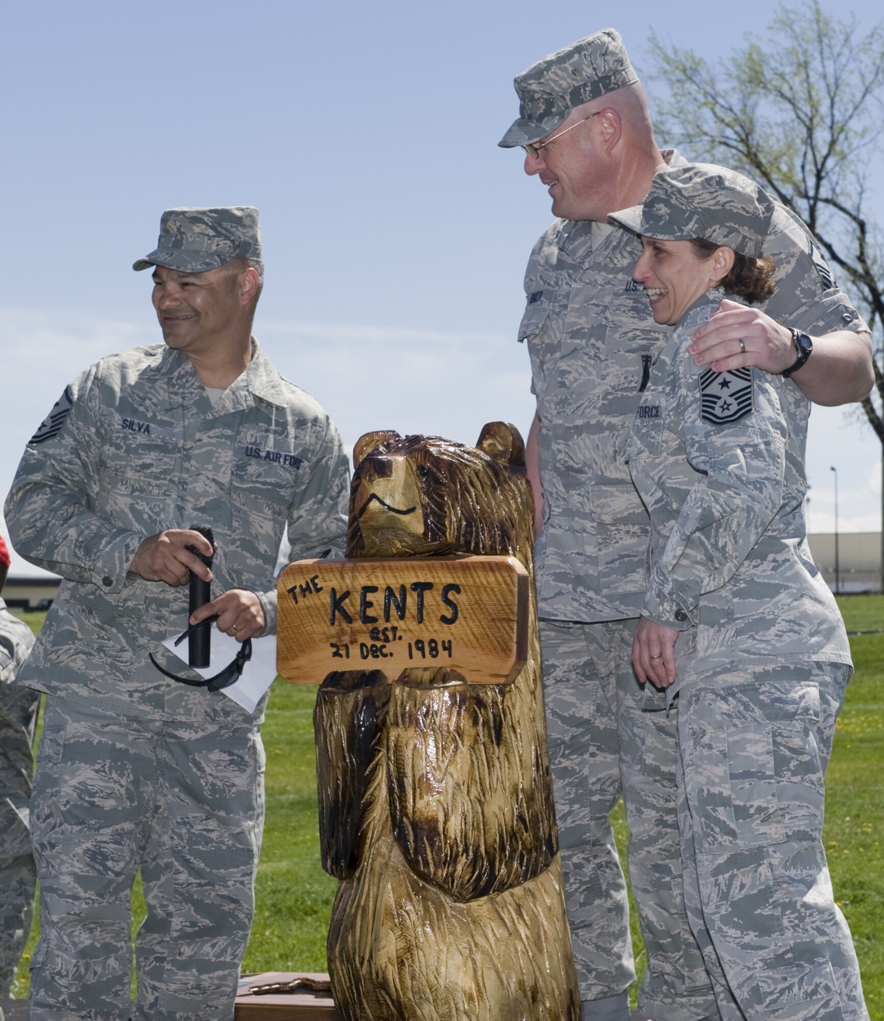 Master Sgt. Timoteo Silva (left), 341st Medical Group first sergeant and Master Sgt. Robert Baker, 341st Operations Group first sergeant, share a lighter moment with Chief Kent at her farewell luncheon May 17. The first sergeants presented Chief Kent with the bear carving, pictured here. (U.S. Air Force photo/Beau Wade)
