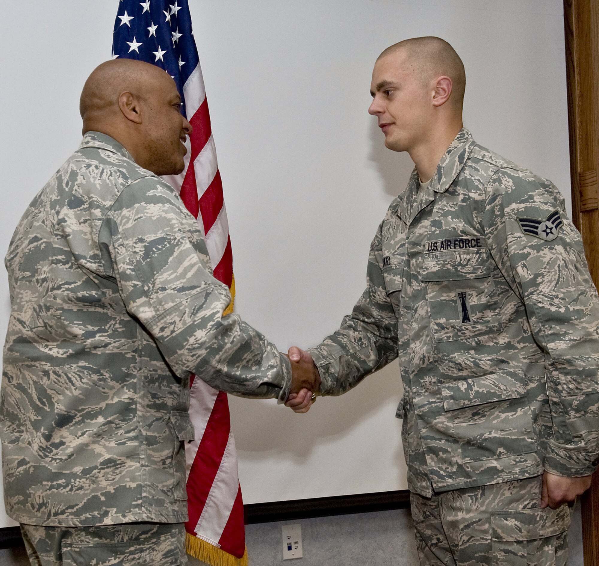 Brig. Gen. (Sel) Anthony Cotton, 341st Missile Wing commander, congratulates Senior Airman Christopher Karl, 341st Missile Maintenance Squadron, for completing his 100th safe driving trip to the missile complex in a payload transporter in the wing conference room May 17.  Airman Karl received a commander's coin. (U.S. Air Force photo/John Turner)