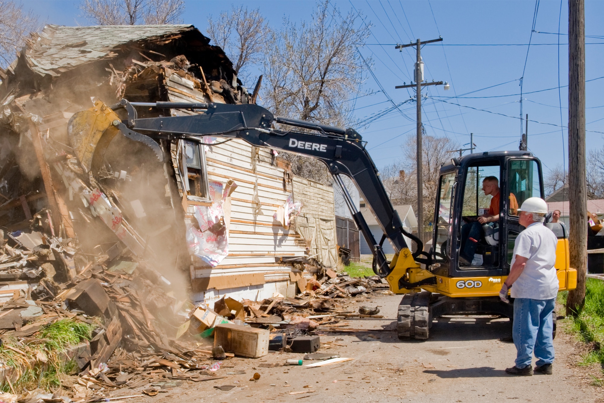 Volunteers bulldoze the walls of a fire-damaged home May 12.  Members of the 819th RED HORSE Squadron and the 341st Security Forces Squadron responded to the call for help when Amanda Parker, 341st Staff Judge Advocate's Office court reporter, asked for assistance in taking down a home at 211 8th Street South that was destroyed by a fire Dec. 30.  Many local community residents also assisted in the demolition efforts.
