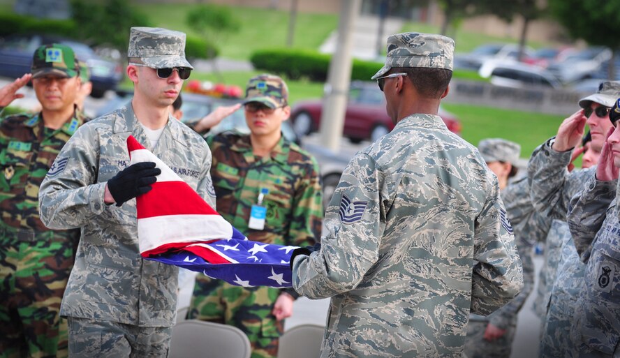 Osan Honor Guard members fold a flag during the ceremonial retreat May 19, honoring Master Sgt. Tara Brown from the Office of Special Investigations and Senior Airman Nicholas Alden from security forces for National Police Week. (U.S. Air Force photo/Staff Sgt. Chad Thompson)
