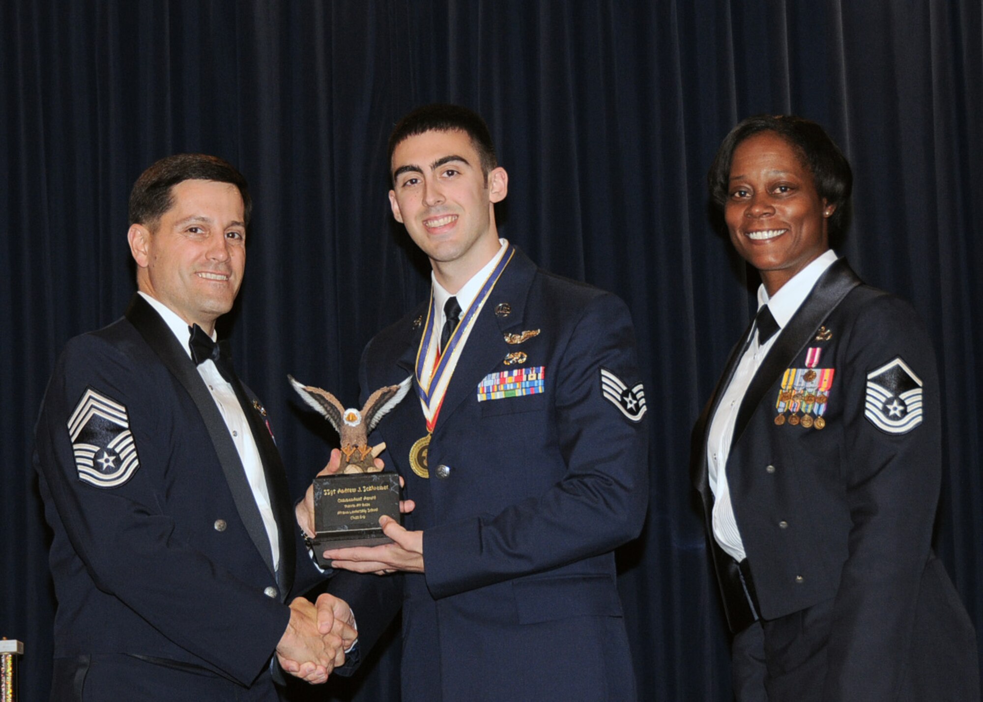YOKOTA AIR BASE, Japan -- Senior Airman Andrew Schloemer, 459th Airlift  Squadron, receives the Commandant Award, from Cheif Master Sgt. James Cornell, 374th Maintenance Group superintendent, during the Airman Leadership School graduation ceremony at Yokota Air Base, Japan, May 19, 2011. (U.S. Air Force Photo/Senior Airman Andrea Salazar)