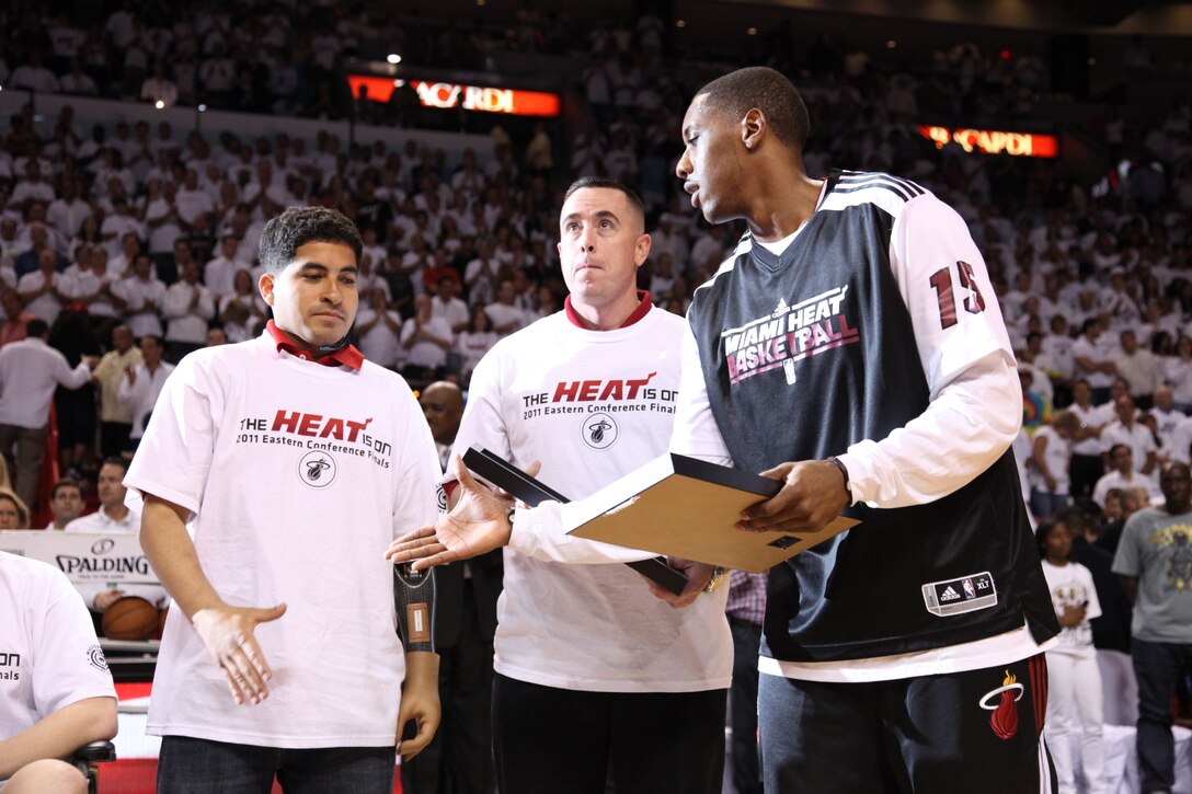 Cpl. Manuel Jiminez is presented with a plaque by Miami Heat guard Mario Chalmers as, 1st Sgt Michael Barrett looks on through the Jumbotron, May 24. Earlier that day, these Marines visited both the U.S. Southern Command Headquarters and U.S. Marine Corps Forces, South Headquarters where they were welcomed and given a tour of both commands. (Photo courtesy of the Miami Heat)