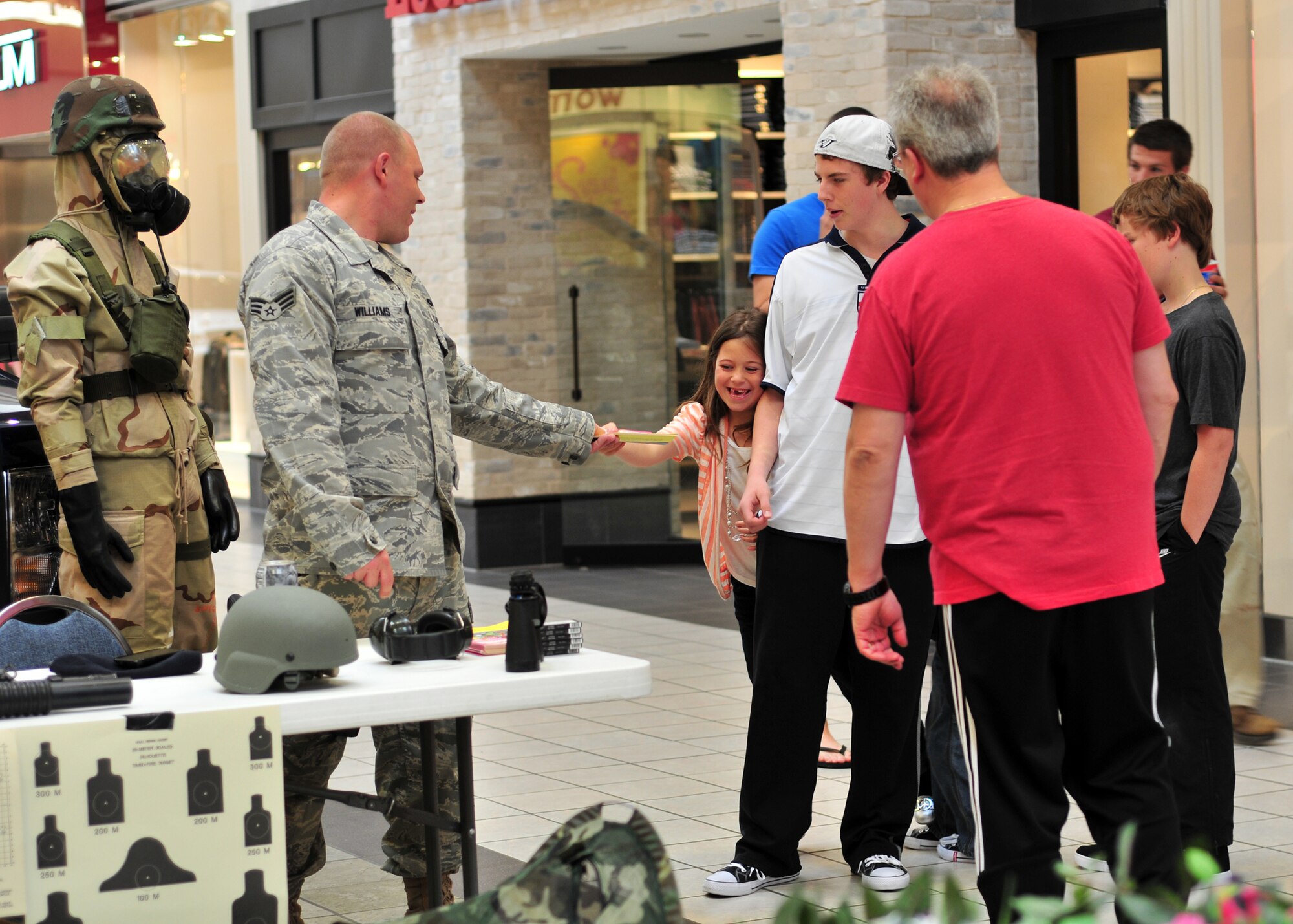 As part of National Police Week 914th Airlift Wing Security Forces member Senior Airman Shane Williams hands out coloring books to children and their families, May 20, 2011, Niagara Factory Outlet Mall, Niagara Falls, NY. Established by a joint resolution of Congress in 1962, National Police Week pays special recognition to those law enforcement officers who have lost their lives in the line of duty for the safety and protection of others. (U.S. Air Force photo by Staff Sgt. Joseph McKee)