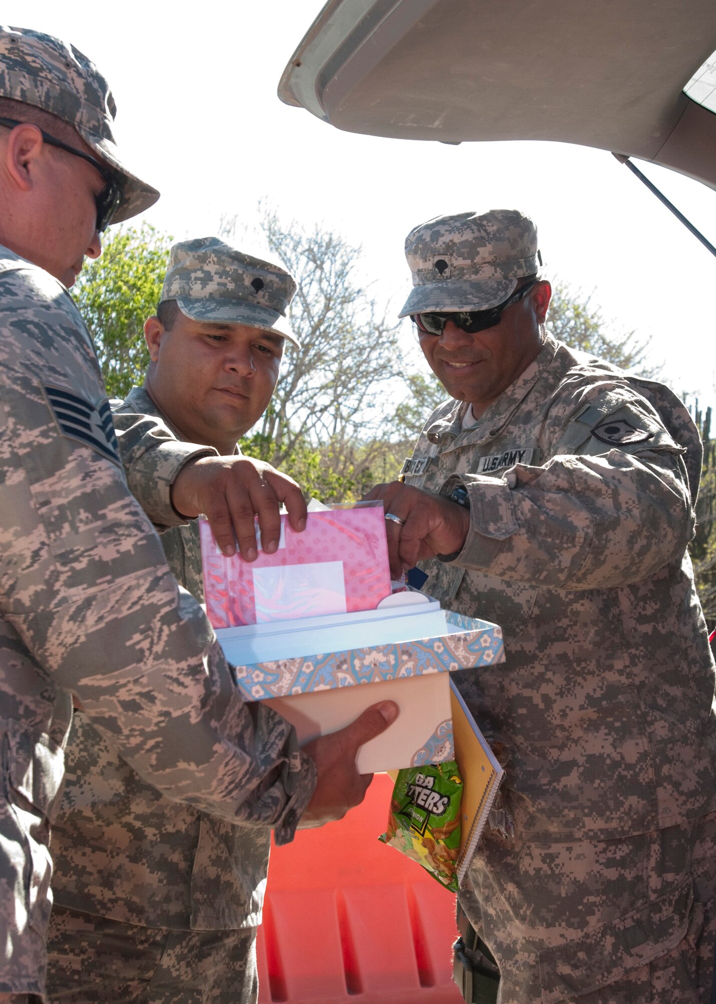 GUANTANAMO BAY, Cuba -- Air Force Staff Sgt. J.T. Peacock, a chaplain's assistant assigned to Joint Task Force Guantanamo, hands out greeting cards to Spc. Harlly Caravallo (left) and Spc. Tony Vargas (right) May 10. Both Caravallo and Vargas are mobilized Puerto Rico National Guardsman with Bravo 296th Military Police Company, which is part of JTF Guantanamo. The cards were sent as part of care packages from citizens back in the United States to provide deployed servicemembers with helpful items and ease the stresses of their deployment. JTF Guantanamo provides safe, humane, legal and transparent care and custody of detainees, including those convicted by military commission and those ordered released by a court. The JTF conducts intelligence collection, analysis and dissemination for the protection of detainees and personnel working in JTF Guantanamo facilities and in support of the War on Terror. JTF Guantanamo provides support to the Office of Military Commissions, to law enforcement and to war crimes investigations.  The JTF conducts planning for and, on order, responds to Caribbean mass migration operations.   (JTF Guantanamo photo by U.S. Navy Mass Communication Specialist 2nd Class Jason Tross) 
