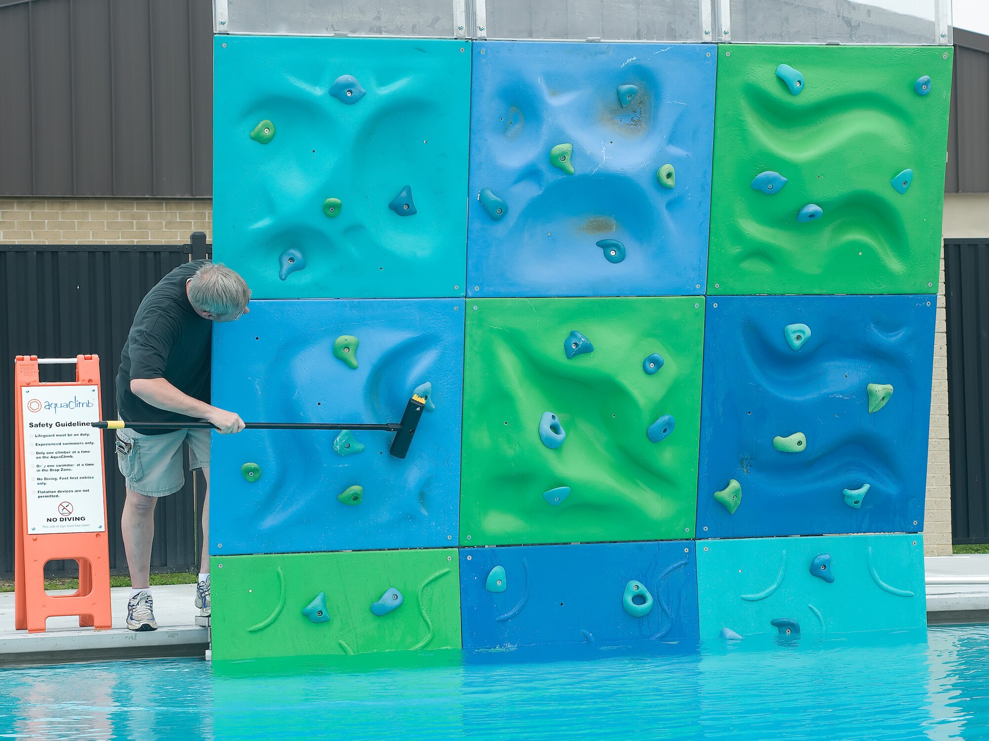 Chris Smith, 436th Force Support Squadron Outdoor Recreation manager, cleans the new climbing wall at the Oasis Swimming Pool, May 23, 2011, at Dover Air Force Base, Del. The pool can accommodate more than 120 swimmers at a time and it officially opens May 28, 2011. (U.S. Air Force photo by Adrian Rowan)