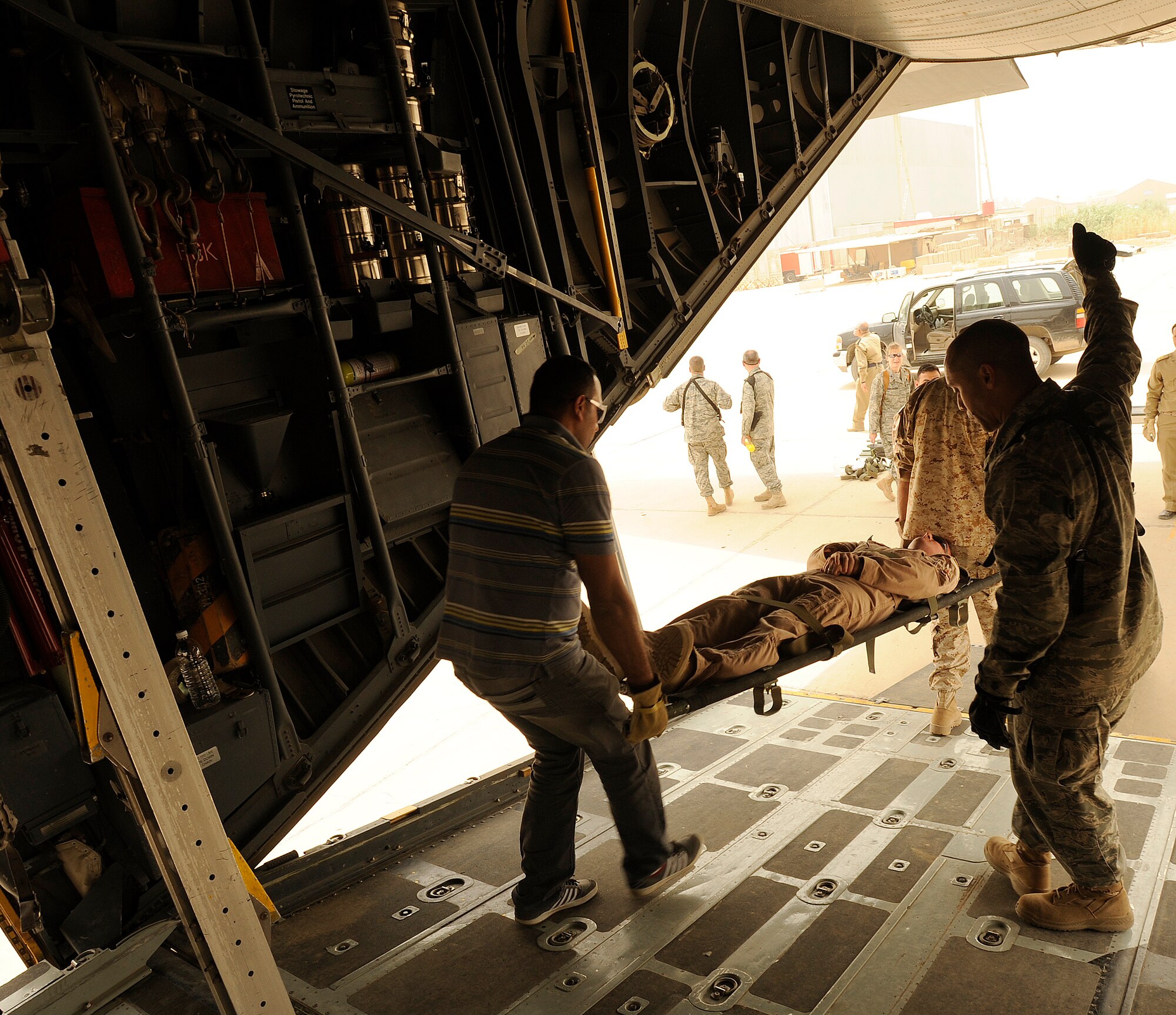 NEW AL-MUTHANA AIR BASE, Iraq -- U.S. Air Force Capt. Reggie Brown, right, 332nd Expeditionary Medical Group critical care nurse, gives a 'thumbs up' as his Iraqi air force counterparts practice loading litters aboard an Iraqi air force C-130 May 19. Six Iraqi medics learned the basics of aeromedical evacuation over two days with U.S. Air Force and Army advisors from three bases. The medics also learned about medical evacuation capabilities for UH-60 Blackhawk, Mi-171 Hip and UH-1 Huey helicopters. Captain Brown is deployed from Eglin Air Force Base, Fla., and hails from Long Island, N.Y. (U.S. Air Force/Tech. Sgt. Jason Lake)
