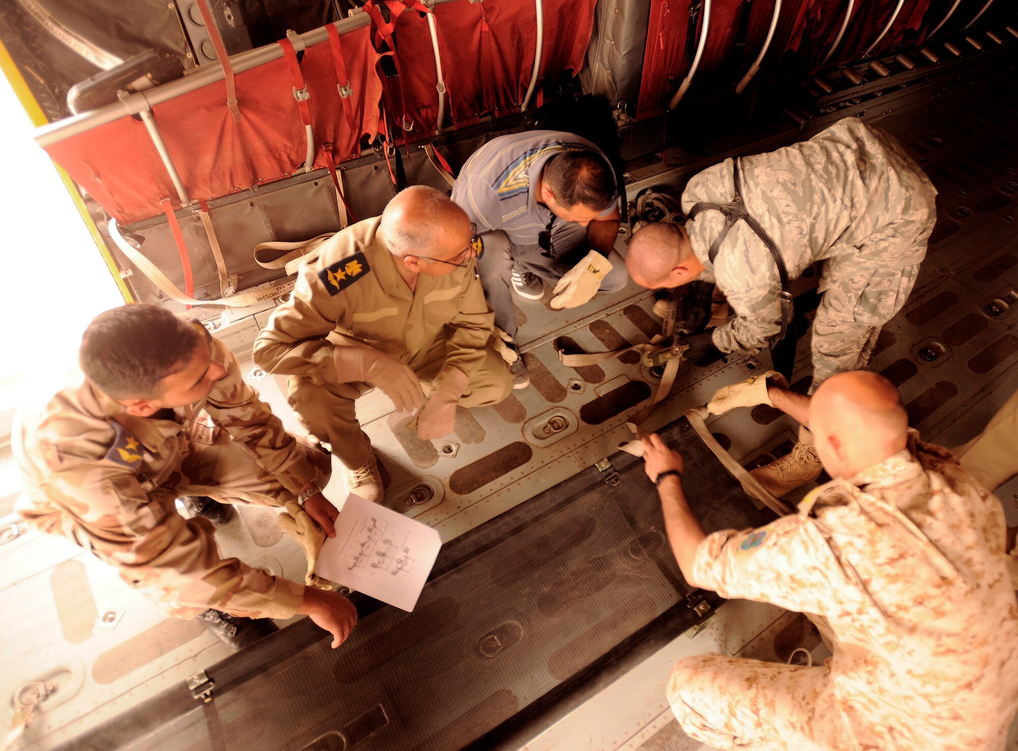 NEW AL-MUTHANA AIR BASE, Iraq -- (right) U.S. Air Force Capt. Reggie Brown, 332nd Expeditionary Medical Group critical care nurse, demonstrates to his Iraqi counterparts how to secure a litter to the floor of an Iraqi C-130 Hercules May 19. Six Iraqi air force medics learned the basics of aeromedical evacuation over two days with U.S. Air Force and Army advisors from Sather Air Base, Joint Base Balad and Camp Taji. The medics learned about medical evacuation capabilities and safety considerations for UH-60 Blackhawk, Mi-171 Hip and UH-1 Huey helicopters. Captain Brown is deployed from Eglin Air Force Base, Fla., and hails from Long Island, N.Y. (U.S. Air Force/Tech. Sgt. Jason Lake)