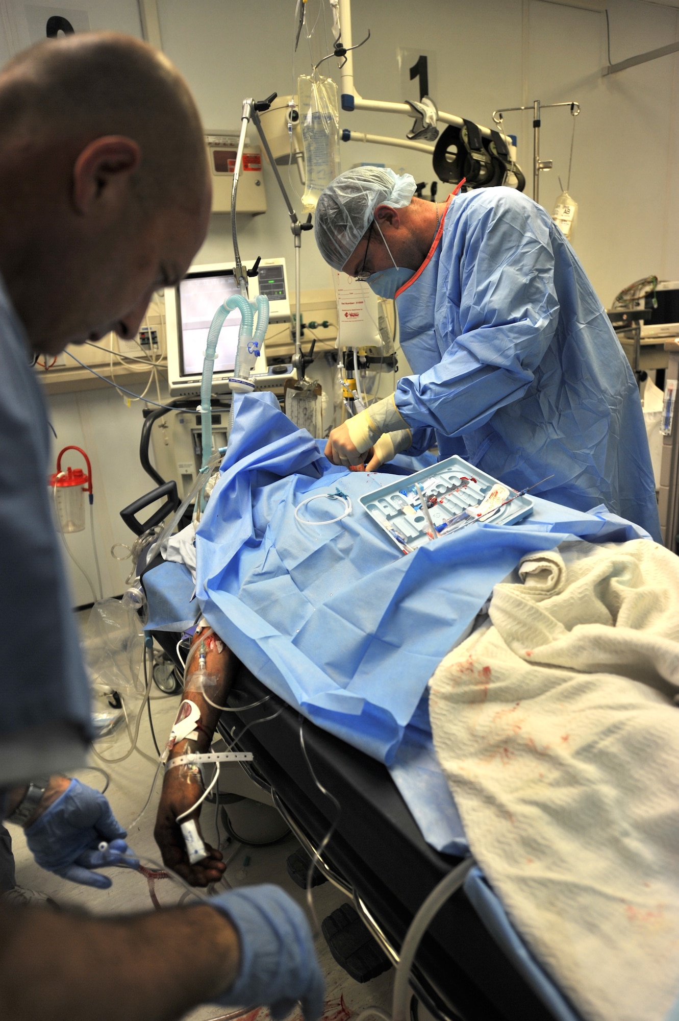 Maj. (Dr.) Travis Girlach a surgeon deployed to the Craig Joint Theater Hospital, Bagram Airfield, Afghanistan installs a central line into a patient's chest to relieve pressure from fuild.  Each day young Americans and Afghans enter into the facility's double-doors and begin what will be the toughest period of their lives. (U.S. Air Force photo by Senior Airman Sheila deVera)