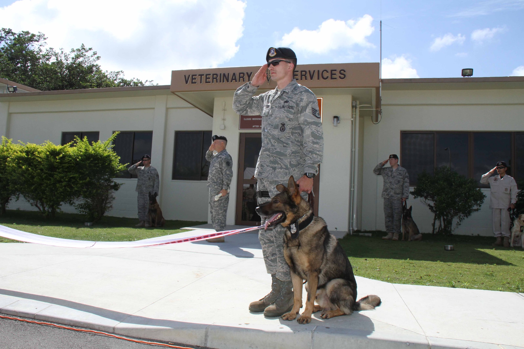 Staff Sgt. Scott Reynolds, an 18th Security Forces Squadron canine handler, salutes during a "Leash" cutting ceremony to celebrate the re-opening of the Okinawa Veterinary Treatment Facility on Kadena Air Base, Japan, May 18. The VTC recently re-opened after major renovations due to the mission out-growing the original facility. (Photo by Chip Steitz)