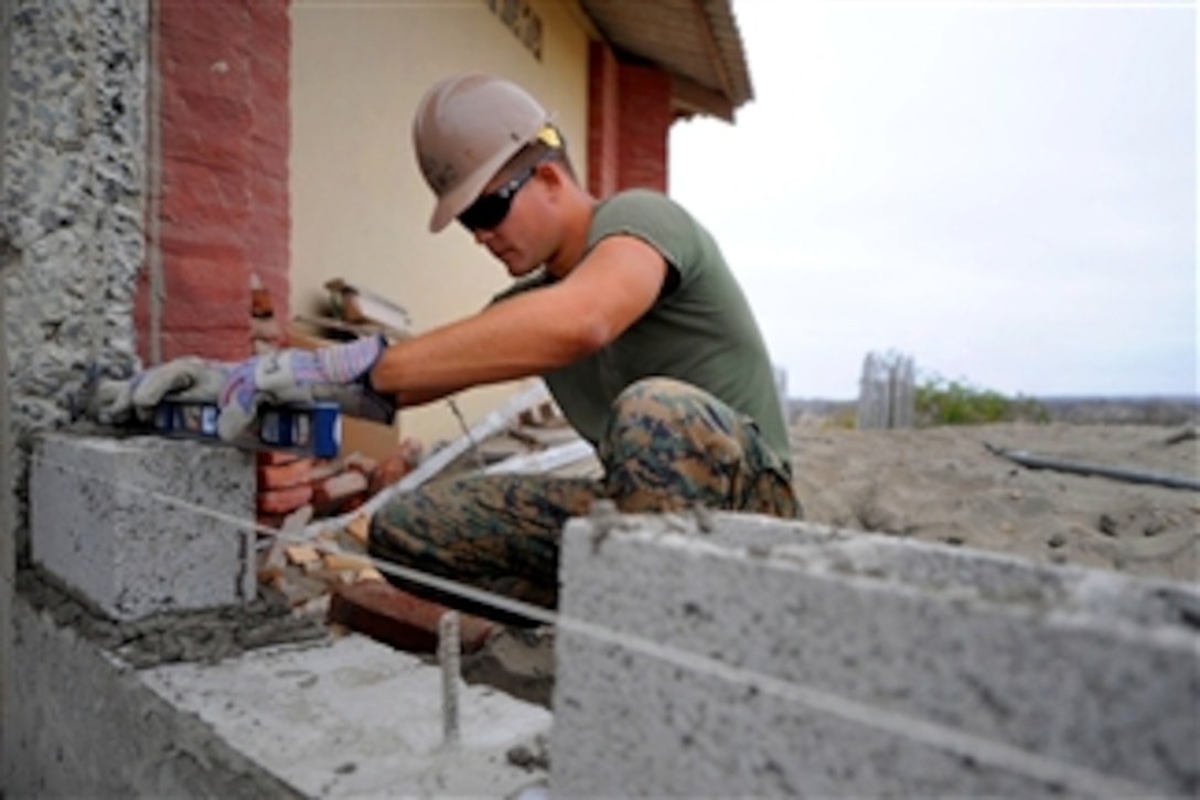 U.S. Marine Corps Cpl. Joe Everetts checks to see if a brick is level while constructing a wall for a new roof at a school during a Continuing Promise 2011 community service project in La Tavesia, Ecuador, on May 17, 2011.  Everetts is assigned to the 8th Engineer Support Battalion.  