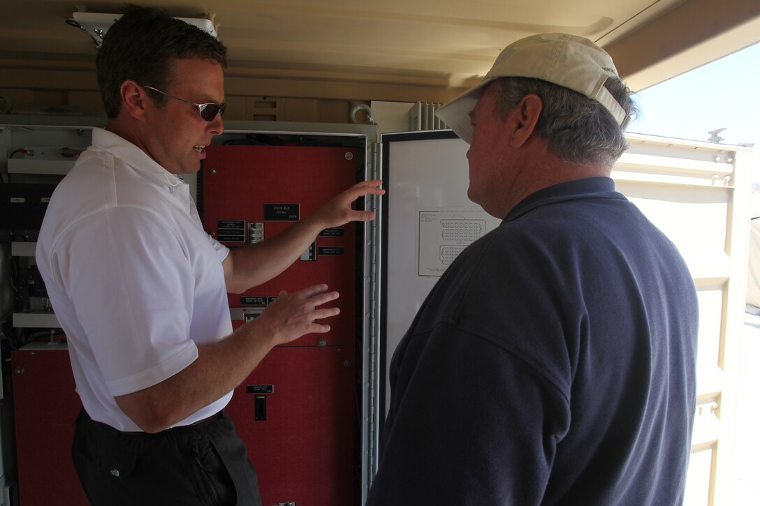 Doug Moorehead [left], the president of Earl Energy, explains how one of his company’s energy efficient systems works to Randall Culberson, an electrical engineer for the Naval Facilities Engineering Command, outside the Marine Corps Training Operations Group headquarters at the Marine Corps Air Ground Combat Center Twentynine Palms, Calif. The Corps is testing several “green initiative” systems designed to boost generator power, cutting fuel costs and prolonging the generators’ life spans. (Official USMC photo by Sgt. Heather Golden)