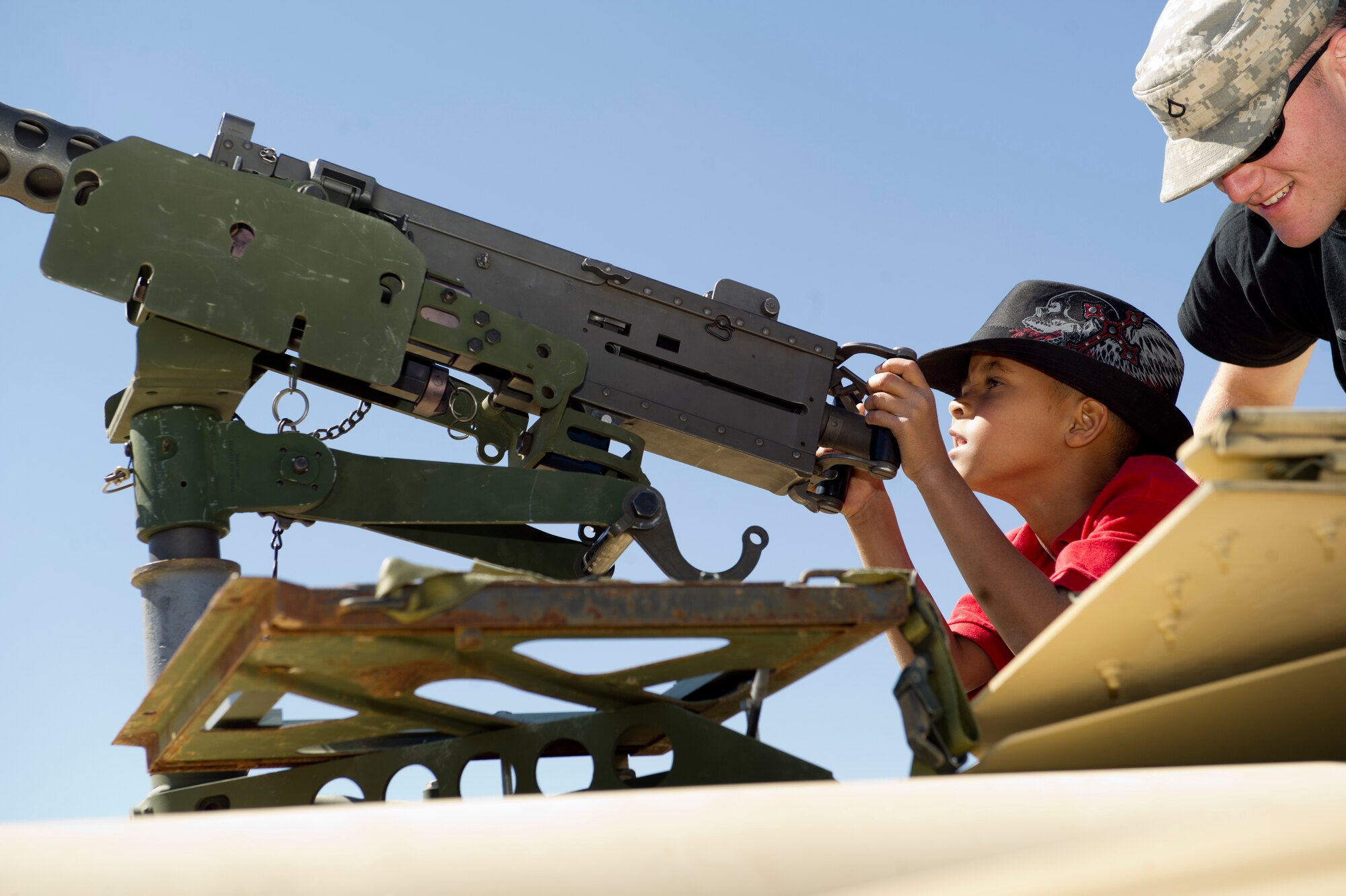 ALAMOGORDO, N.M. -- Seven-year-old Deauntae Seitz looks through a .50-caliber Browning machine gun wih Private 1st Class Joey Stephen, N.M. Army National Guard, Delta Company, during Armed Forces Day, May 21, 2011, at Washington Park. Infantry soldiers allowed people to climb inside of a HMMWV to get a feel for what military members drive while deployed. (U.S. Air Force photo by Senior Airman Veronica Stamps/Released)