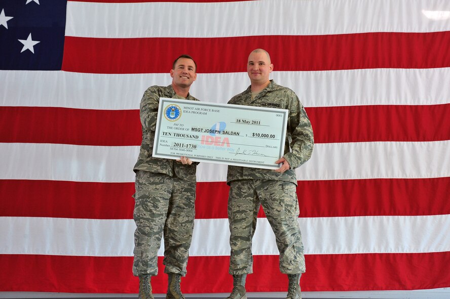 MINOT AIR FORCE BASE, N.D. -- Innovative Development through Employee Awareness award winner, Master Sgt. Joseph Saldan, 91st Missile Maintenance Squadron NCO in charge of the Electro-Mechanical Team section, receives a check for 10,000 dollars from Lt. Col. Joel Hanson, 91 Maintenance Group Commander here May 18. Air Force Global Strike Command awarded a maximum payout of $10,000 for his submission to the IDEA program. The program encourages Airmen and Air Force employees to look for ways of doing the Air Force business, faster, better and cheaper. (U.S. Air Force Photo/Senior Airman Jesse Lopez)