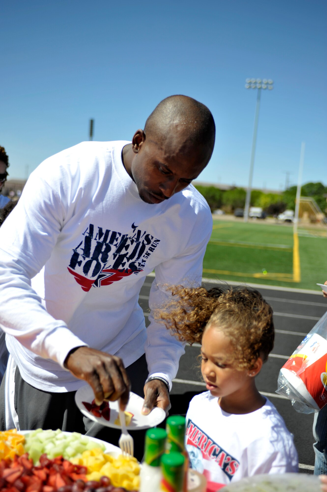 U.S. Air Force Senior Airman Courtney Jones, 27th Special Operations Aircraft Maintenance Squadron, fixes a plate of fruit for his daughter Jayah, 5, at Cannon Air Force Base, N.M. May 21, 2011. Fruit and vegetables were served at the end of the competition in order to promote healthy eating as part of May, National Fitness Month. (U.S. Air Force photo by Airman Ericka Engblom)