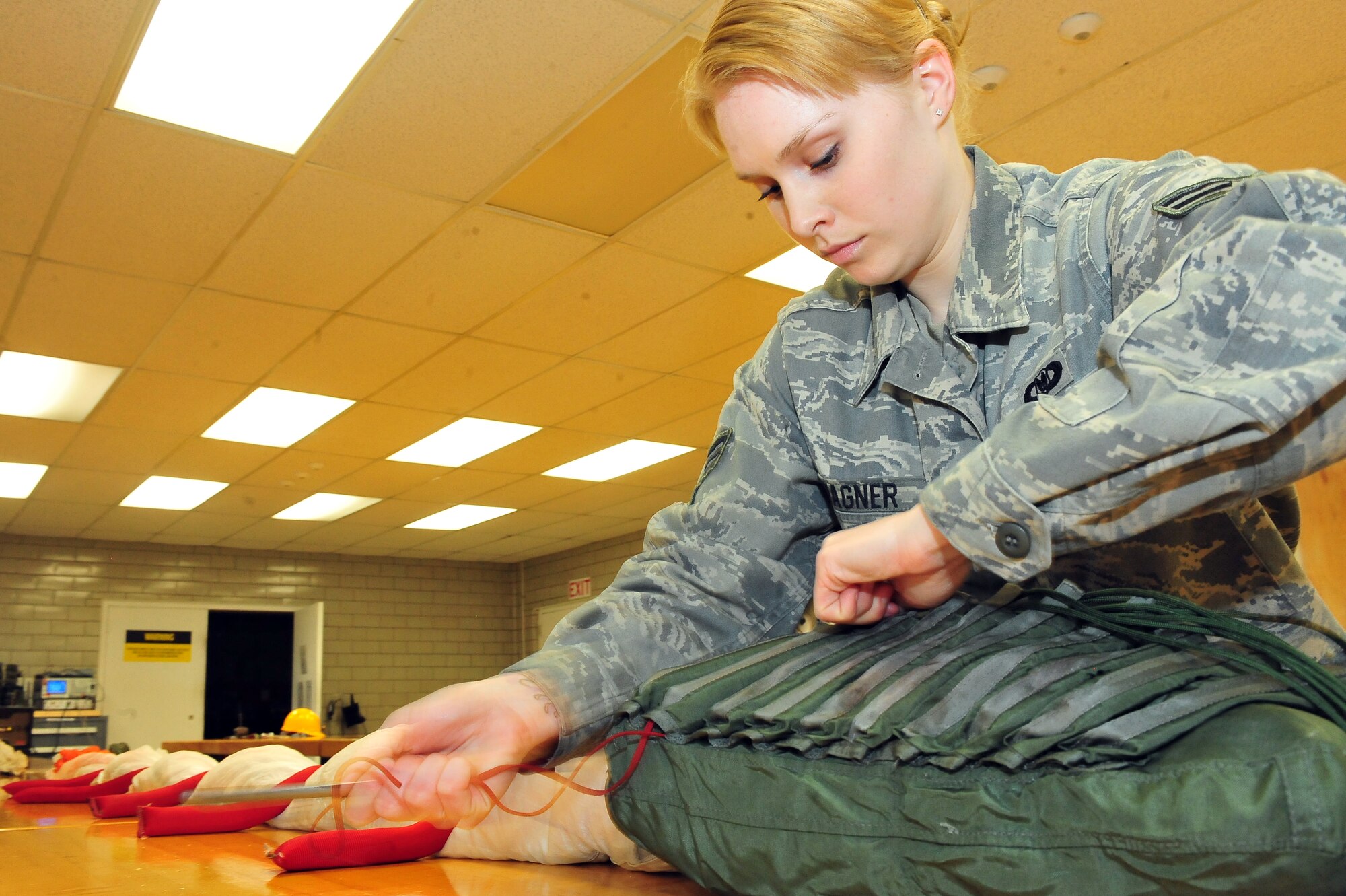 MINOT AIR FORCE BASE -- Airman 1st Class Danni Wagner, 5th Operations Support Squadron aircrew flight equipment technician, packs and compresses parachute survival kits at the AFE parachute shop here May 16. Aircrew flight equipment members inspect and maintain life-saving appliances and gear for the B-52H Stratofortress, as well as all 5th Bomb Wing aircrew personnel. (U.S. Air Force Photo/Senior Airman Jesse Lopez) 