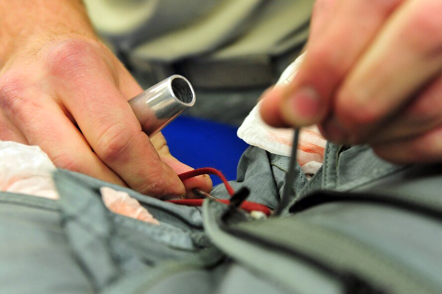 MINOT AIR FORCE BASE -- Senior Airman Cody Lytle, 5th Operations Support Squadron aircrew flight equipment technician, aids in mending parachute survival kits by fastening together rips at the AFE parachute shop here May 16. Aircrew flight equipment members inspect and maintain life-saving appliances and gear for the B-52H Stratofortress, as well as all 5th Bomb Wing aircrew personnel. (U.S. Air Force Photo/Senior Airman Jesse Lopez) 