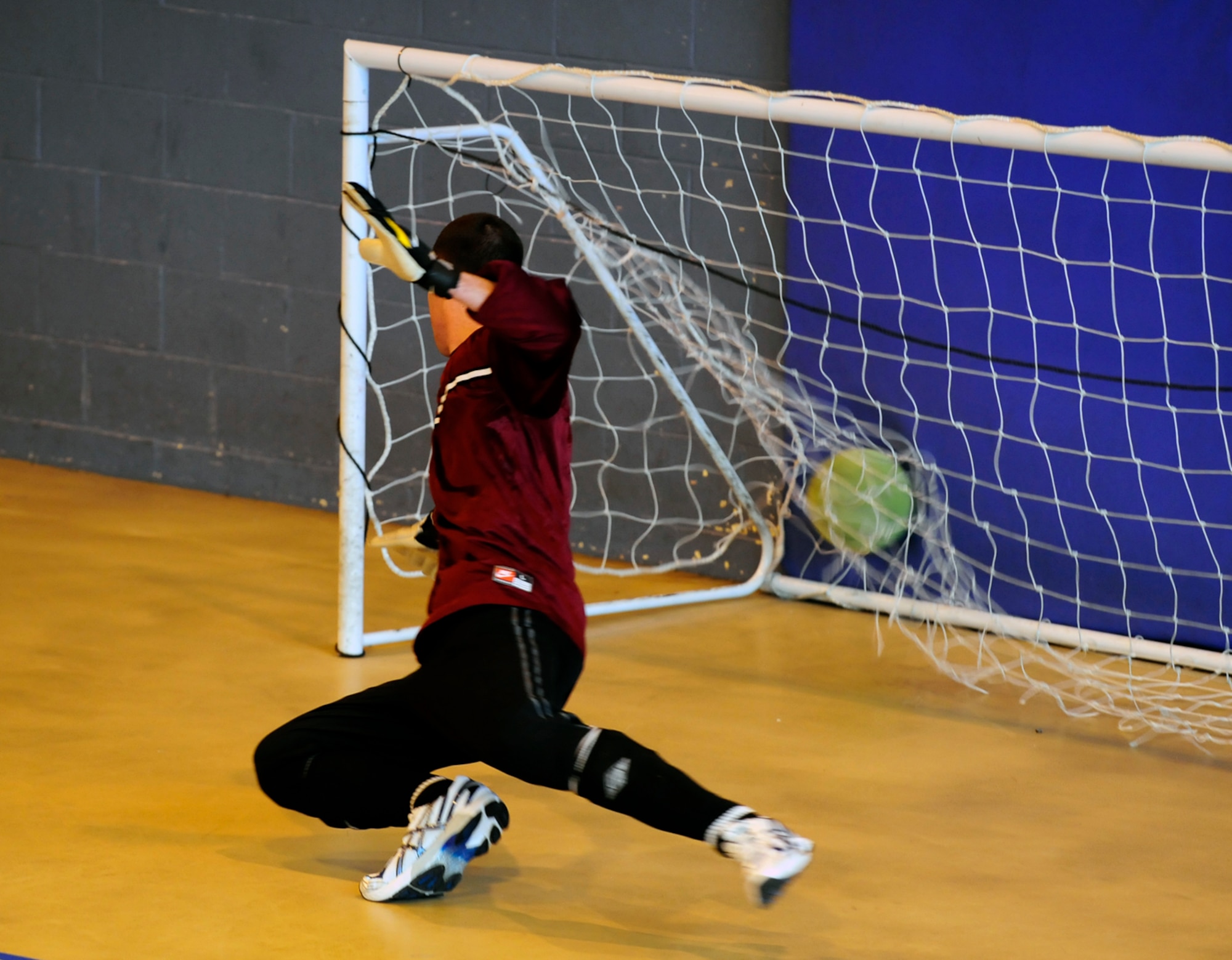 RAF MILDENHALL, England  -- Kenneth King, the 352nd Special Operations Group  keeper, dives in vain, as a powerful shot from Aaron Cooper flies in the back of the net. King’s team were beaten 8-1 by the 100th Civil Engineer Squadron, in the RAF Mildenhall Intramural Indoor Soccer Championship at the North Side Fitness Center, May 20, 2011. (U.S. Air Force photo/Senior Airman Ethan Morgan)