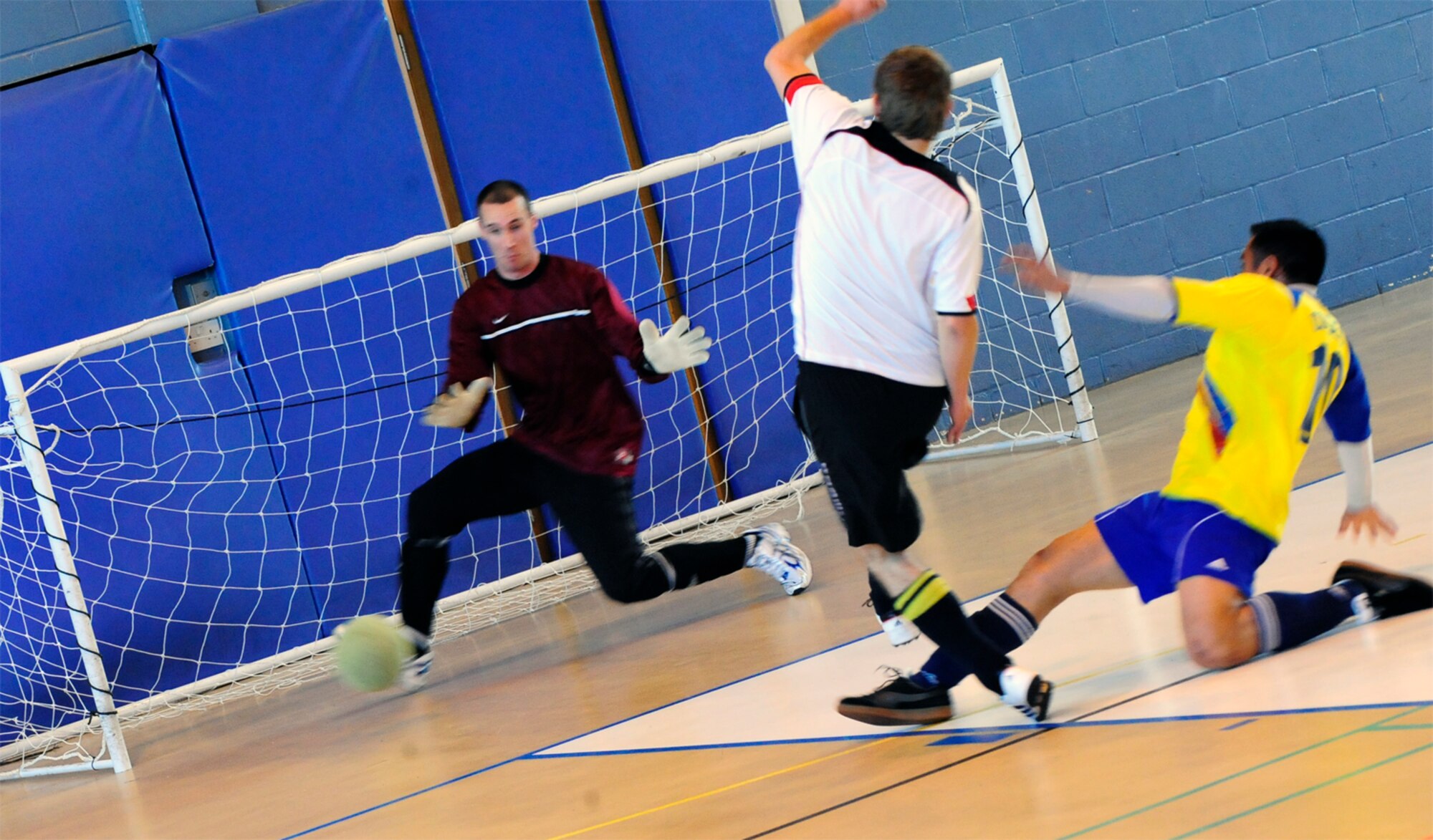 RAF MILDENHALL, England  -- Geoff Gough (white shirt), scores the opening goal for the 100th Civil Engineer Squadron in the RAF Mildenhall Intramural Indoor Soccer Championship at the North Side Fitness Center, May 20, 2011. CE defeated the 352nd Special Operations Group 8-1 to win their third straight championship. (U.S. Air Force photo/Senior Airman Ethan Morgan)