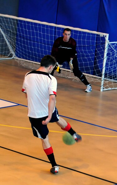 RAF MILDENHALL, England -- Aaron Cooper (white shirt), volleys the ball past Kenneth King to complete his hat-trick to increase the 100th Civil Engineer Squadron’s lead in the RAF Mildenhall Intramural Indoor Soccer Championship at the North Side Fitness Center, May 20, 2011. Cooper scored four stunning goals in their 8-1 defeat of the 352nd Special Operations Group.  This was CE’s third straight Championship win and the second year in a row that Cooper has been the key player. (U.S. Air Force photo/Senior Airman Ethan Morgan)