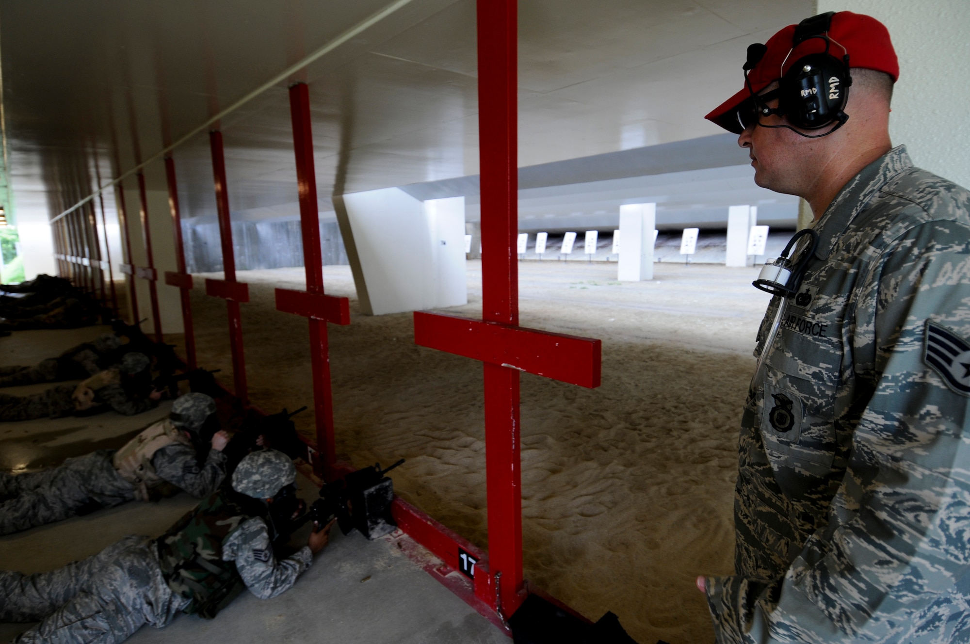 An 18th Security Forces Combat Arms instructor watches as qualifying Airmen take aim and await the command of "fire" during the gas masks portion of the qualification at the newly-refurbished CA firing range May 24. Though only about 75 percent complete with renovations, roughly 100 soon-to-deploy Airmen are now passing through the range each week to qualify on their appropriate weapons. (U.S. Air Force photo/ Airman 1st Class Maeson L. Elleman)