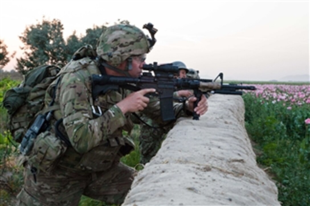 A U.S. Army soldier with Charlie Company, 2nd Battalion, 502nd Infantry Regiment, 101st Airborne Division, aims his M4 carbine over a wall while securing an open field in Char Shaka, Kandahar province, Afghanistan, on April 27, 2011.  