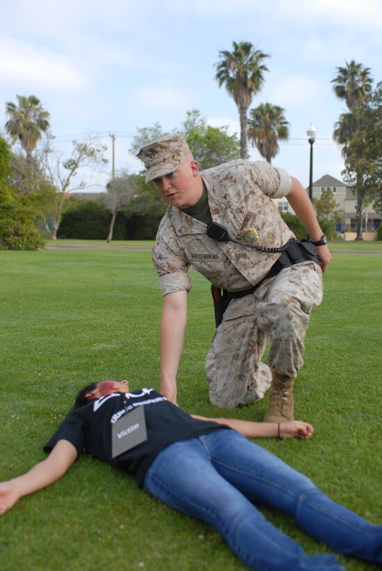 Lance Cpl. Paul D. Rosenberg, military police at MCRD, helps assist simulated victims during Aztec Fury. A man took out two gate guards then drove his car into a CG's event leaving wounded Marines behind for the exercise.