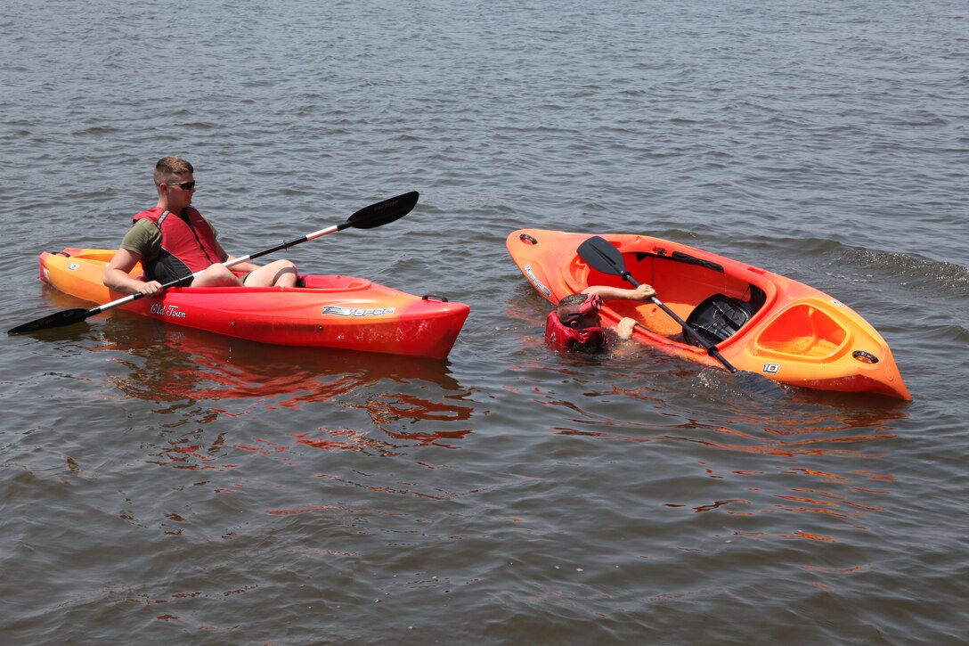 Lance Cpl. Caleb M. Morris, right, a UH-1N crew chief with Marine Light Attack Helicopter Squadron 467, attempts to right himself after capsizing his kayak during the drunken goggle kayaking portion of the boater’s safety lesson at the Pelican Point Marina May 26. This was one of the interactive safety brief classes put on by HMLA-467 for its Marines.