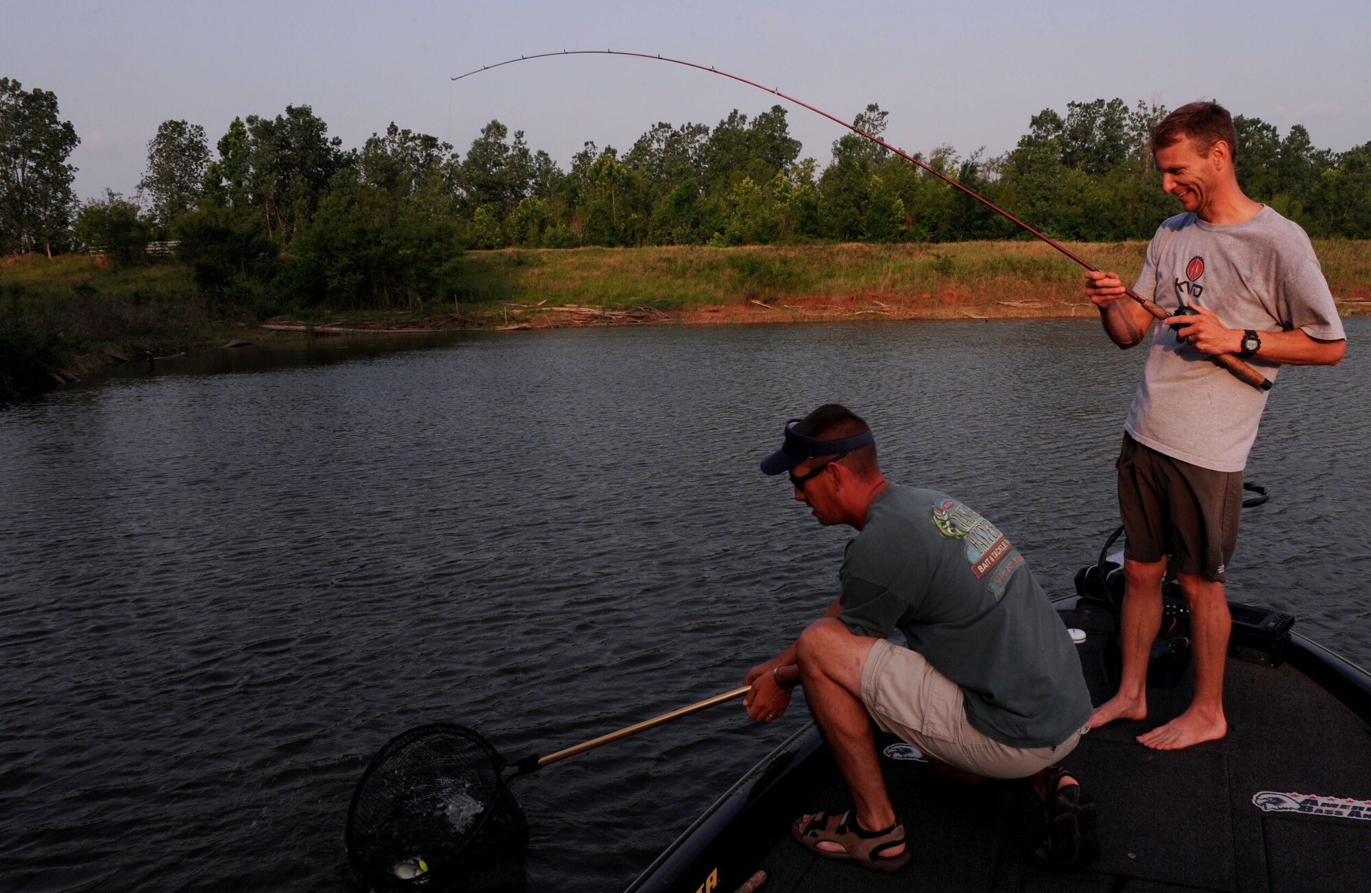 Senior Master Sgt. Greg Korkoske, Air Force Global Strike Command, reels in a fish out on the Red River South Marina in Bossier City, La., as Tech. Sgt. Christopher Waywand, 2nd Munitions Squadron, helps out May 25. The fishing tournament was the start of Sports Day, which was designed to improve teamwork and promote the Air Force's Fit-to-Fight mission. (U.S. Air Force Photo/Senior Airman La'Shanette V. Garrett) (RELEASED) 